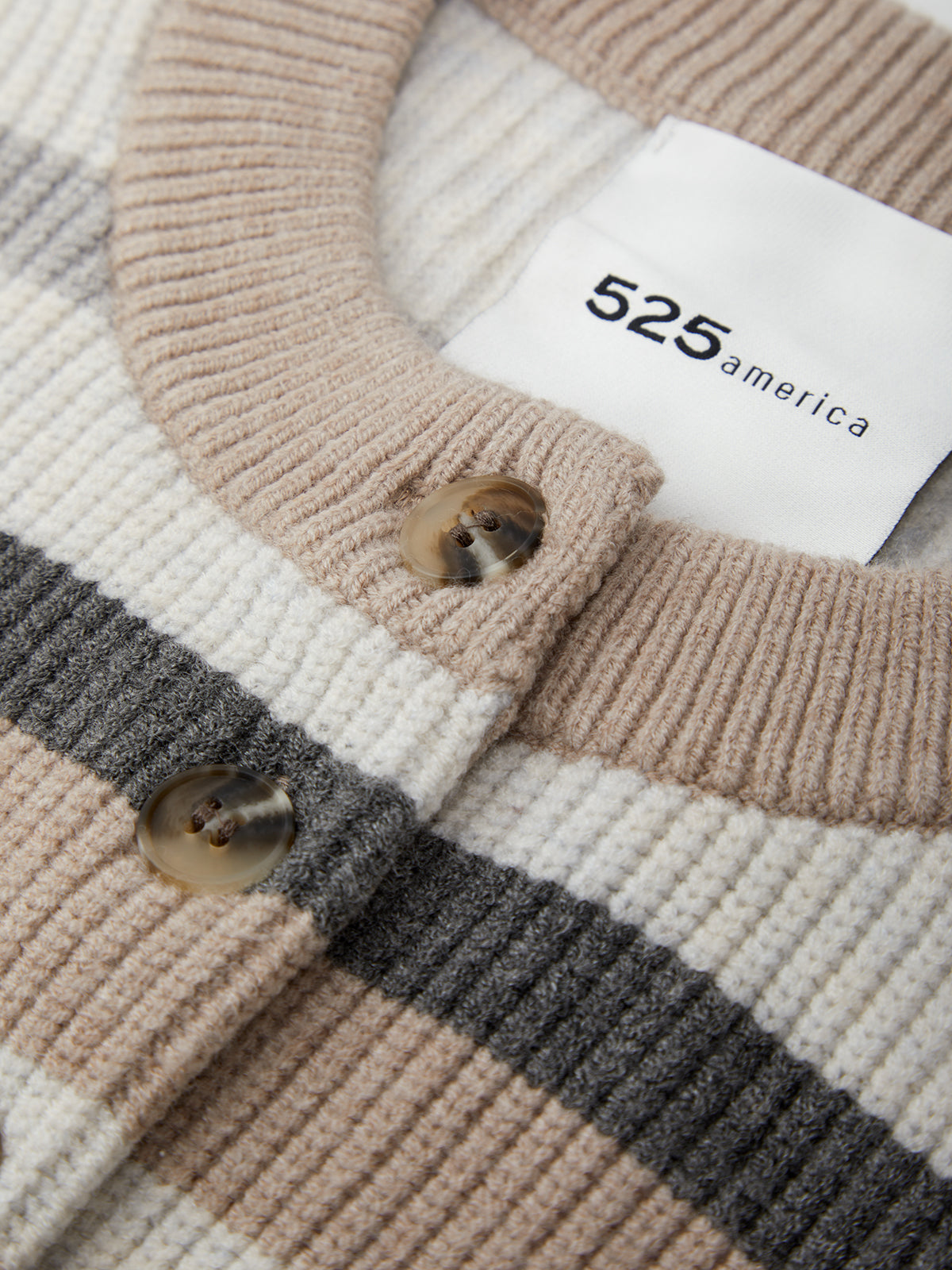 Close-up of a striped sweater with a brand label on a neutral background
