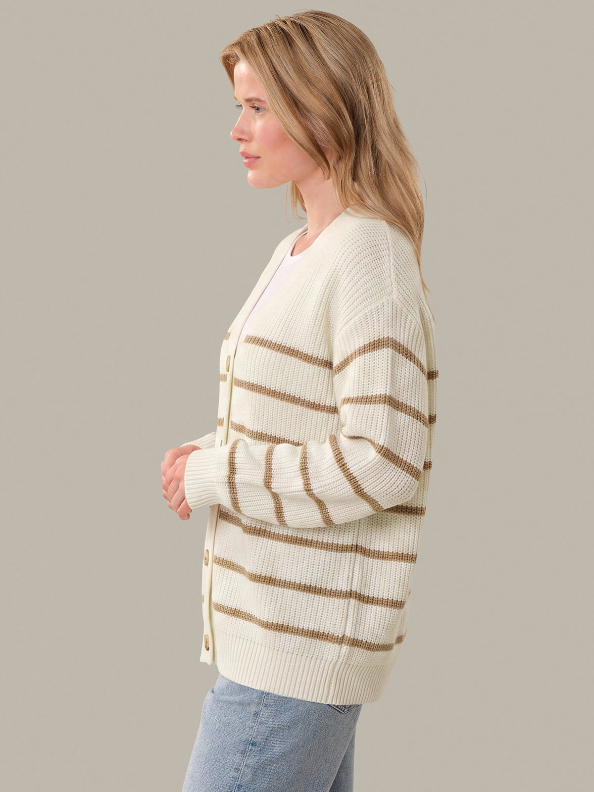 Woman wearing a cream and brown striped cardigan against a plain background