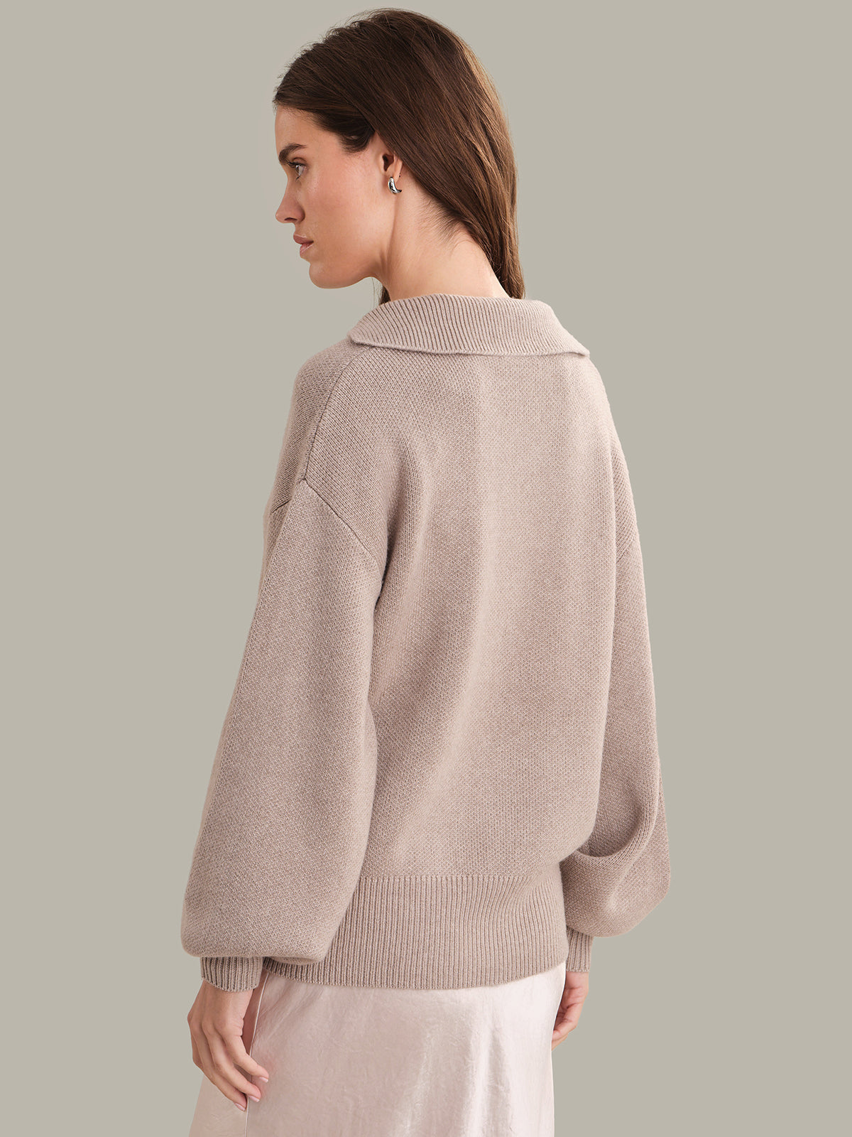 Woman wearing a beige sweater against a plain background