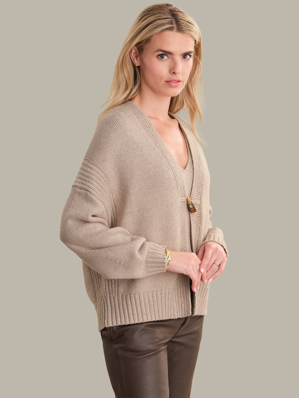 Woman wearing a beige sweater with a plain background