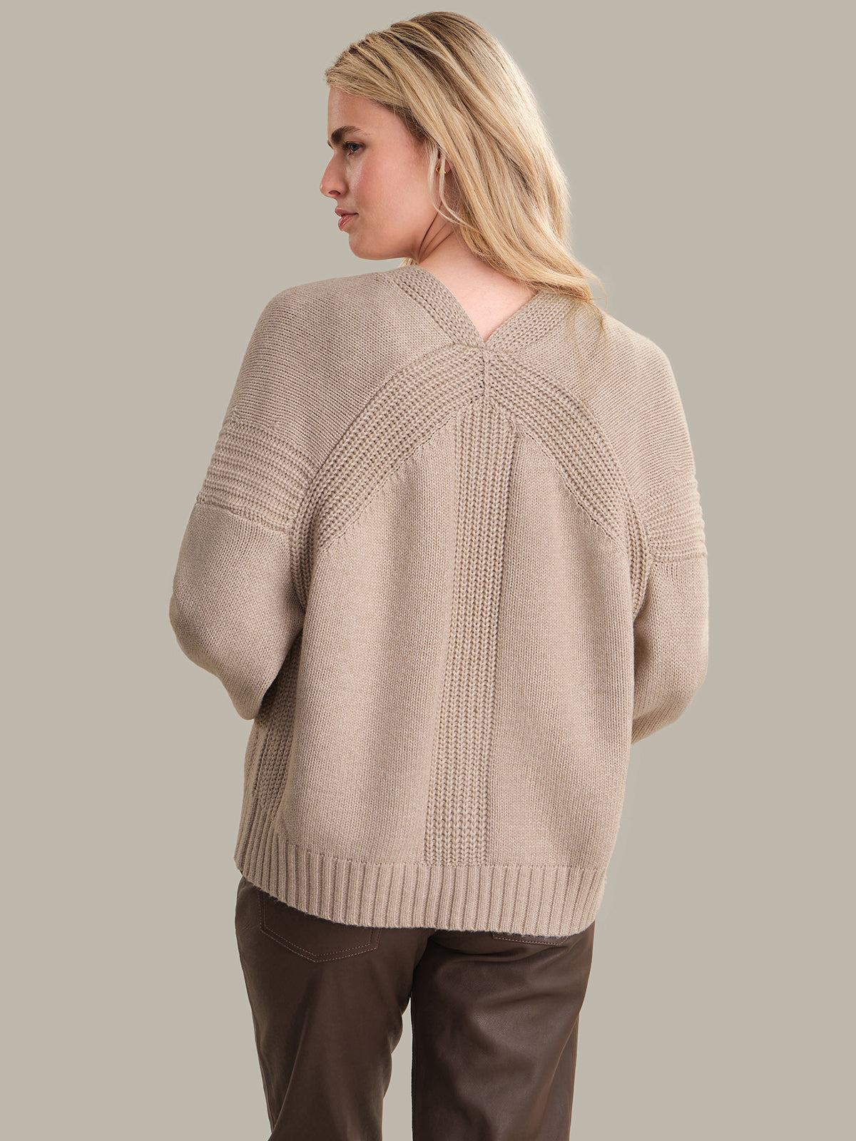Woman wearing a beige cardigan with a neutral background