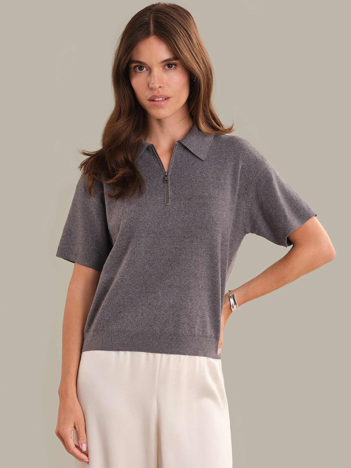 Woman wearing a gray short-sleeve shirt with a collar on a plain background