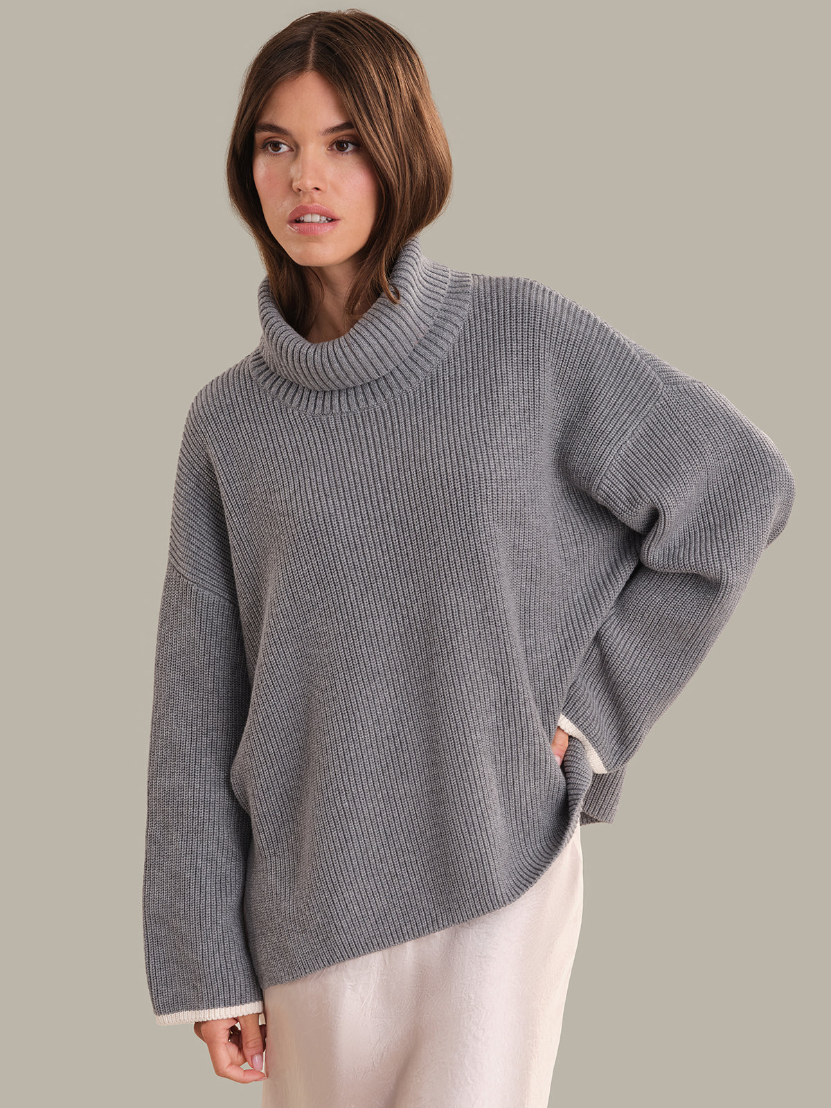 Woman wearing a gray sweater against a plain background