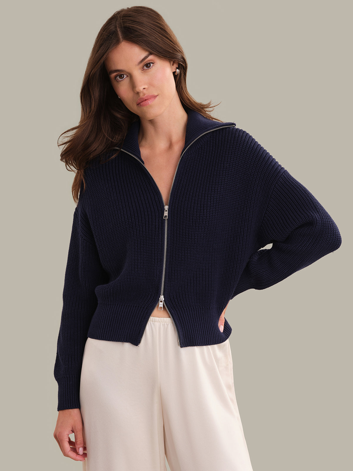 Woman wearing a navy blue zip-up sweater against a neutral background