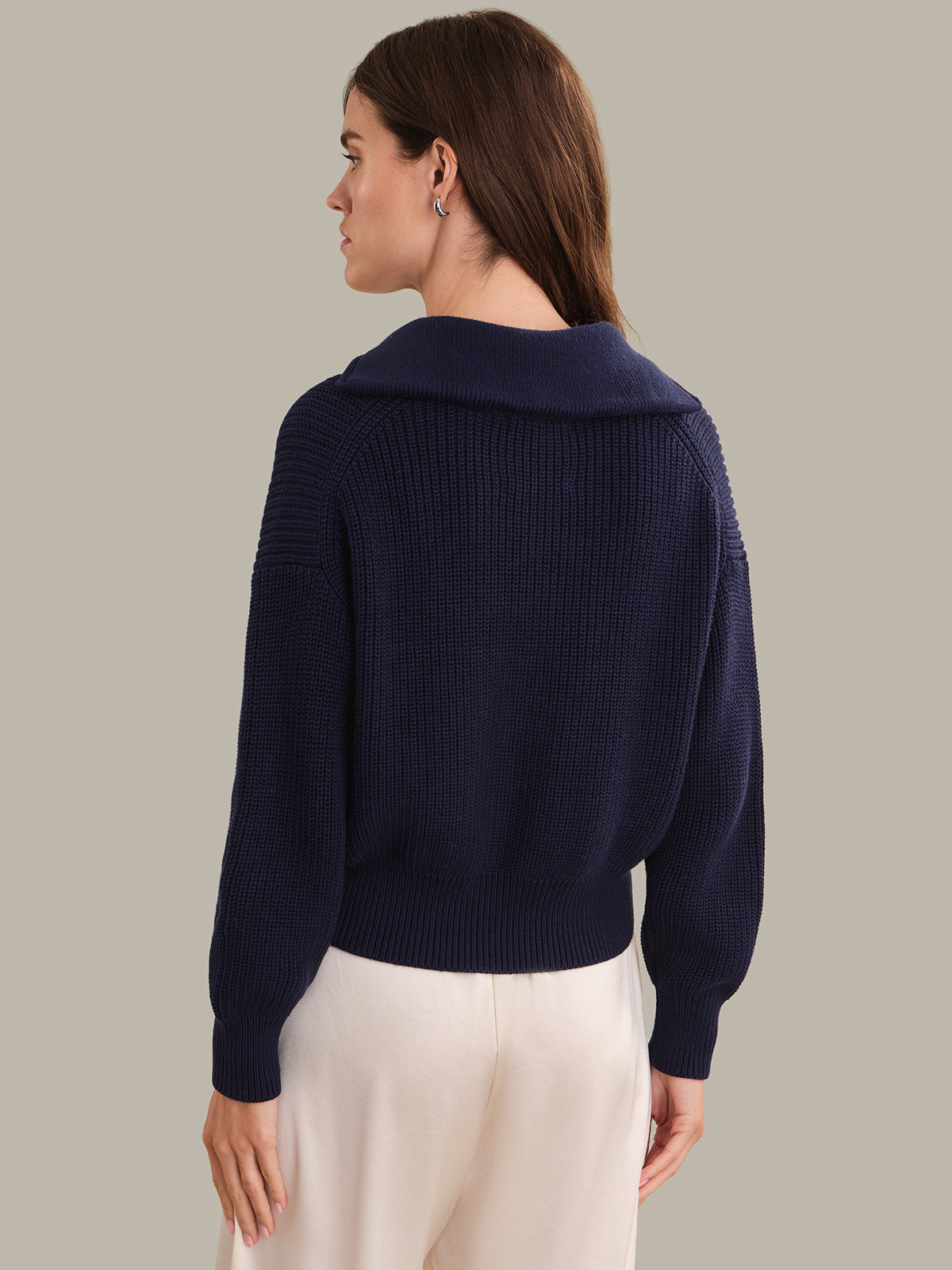 Woman wearing a navy blue sweater against a plain background