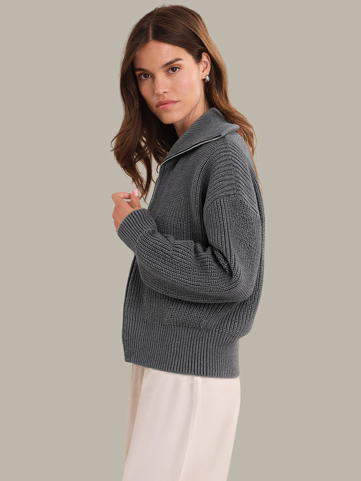 Woman wearing a gray knitted sweater against a plain background