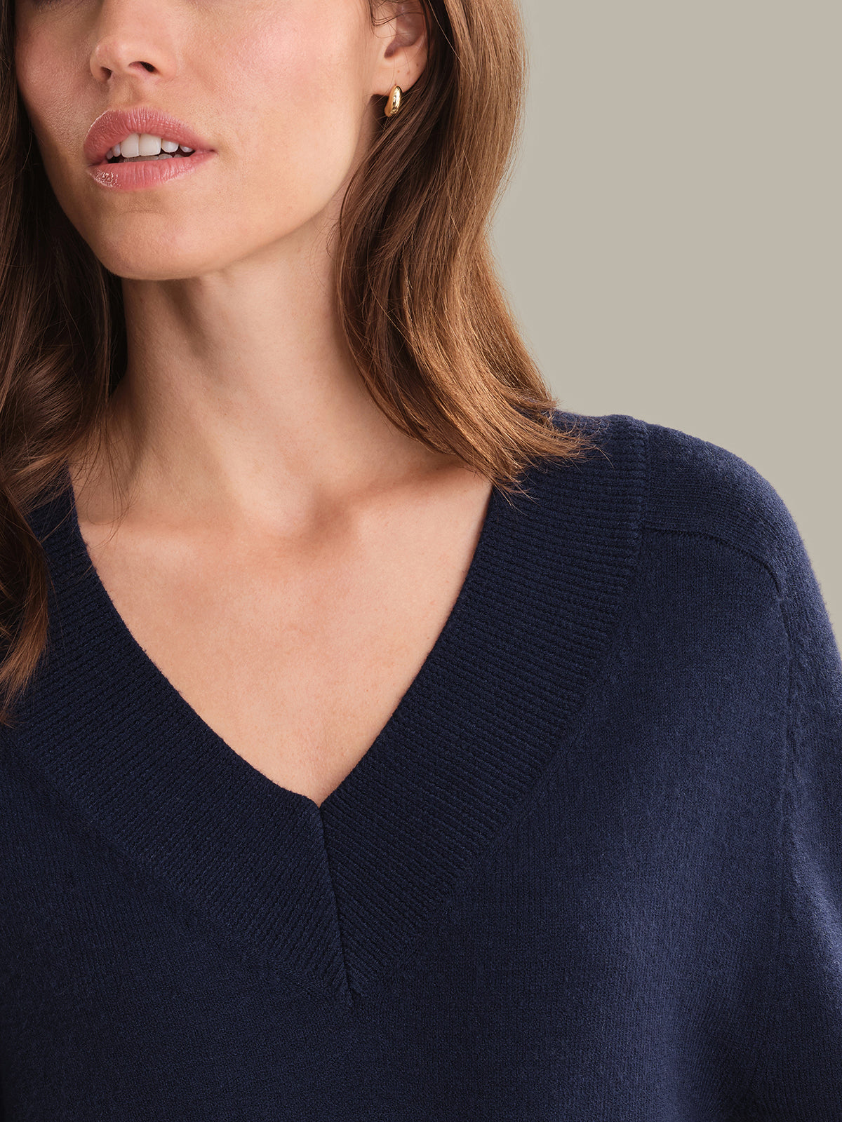 Woman wearing a navy blue sweater against a neutral background