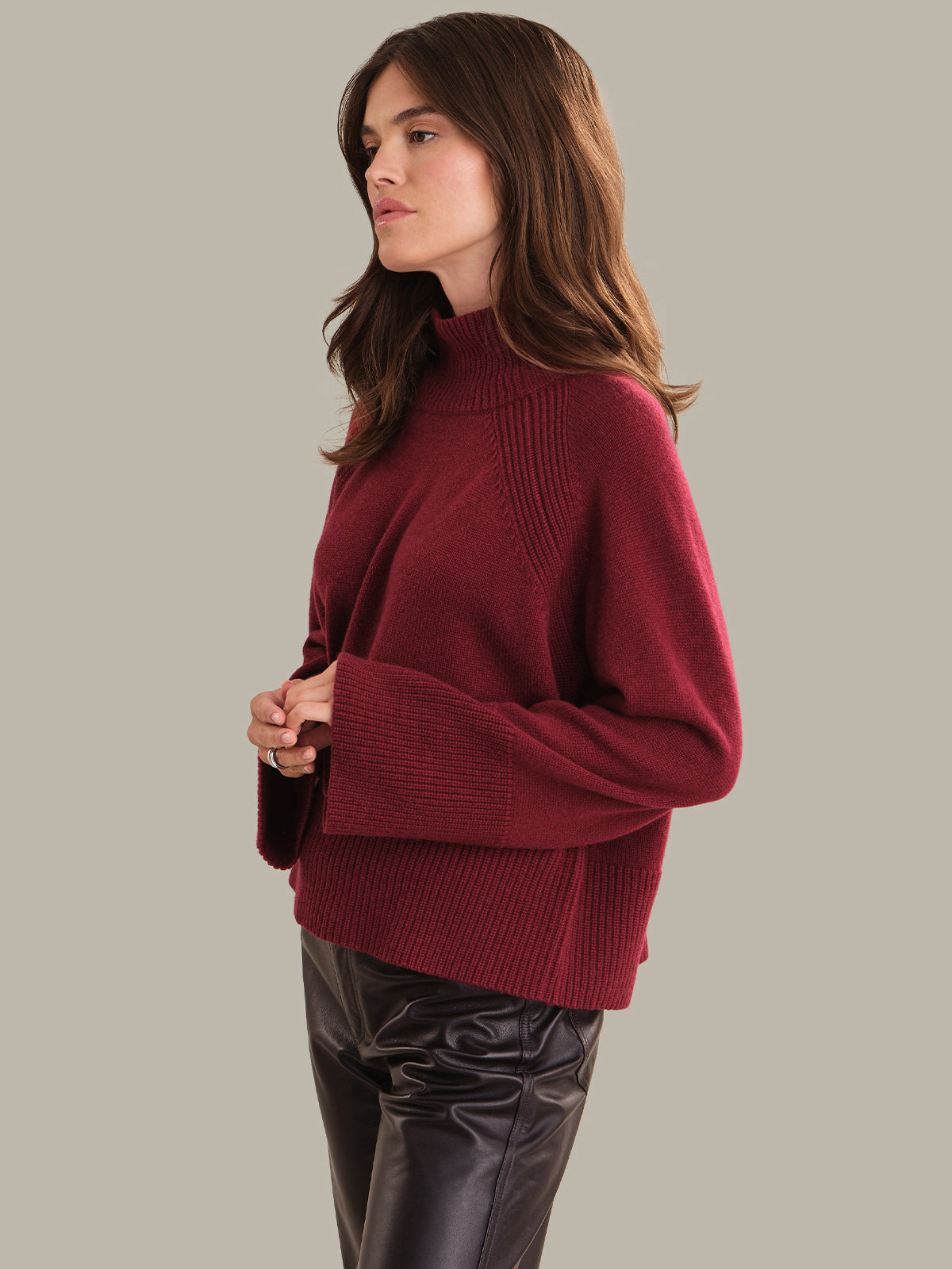 Woman wearing a burgundy sweater against a neutral background