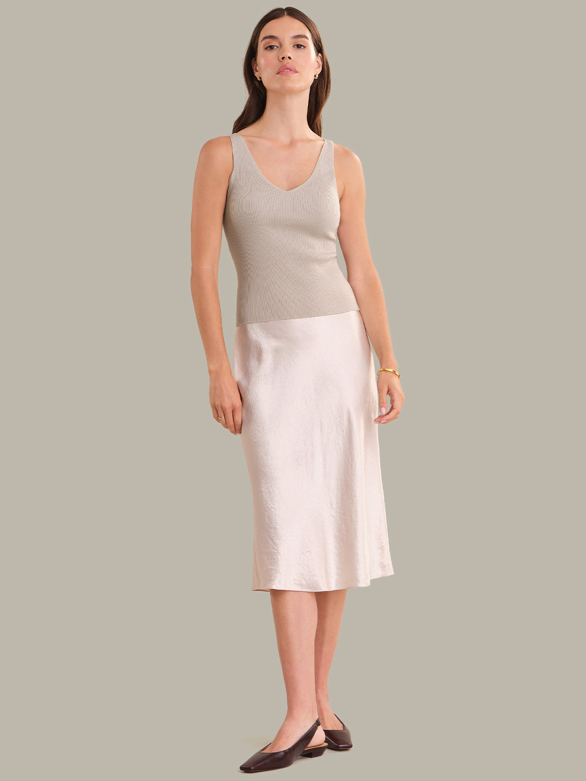 Woman wearing a sleeveless top and skirt on a plain background