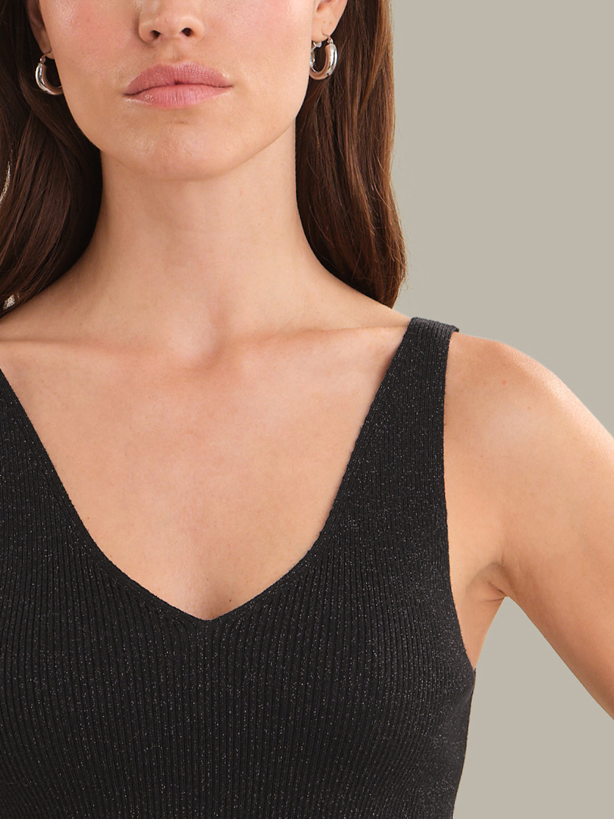 Woman wearing a black sleeveless top against a neutral background