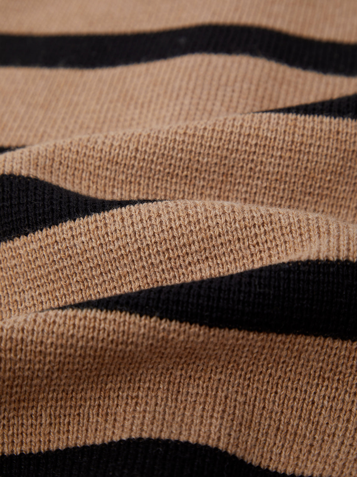 A close-up of a 525 America knitted stripe cardigan with horizontal tan and black stripes showcases its textured, raised wavy surface for a sophisticated twist on a timeless design.