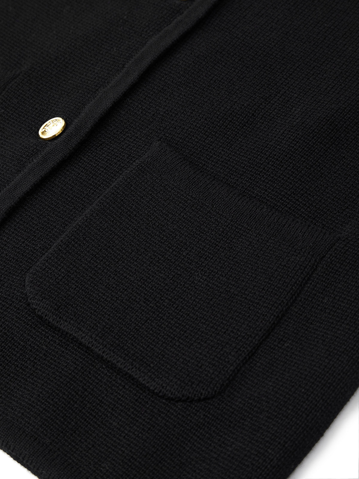 Close-up of a black jacket with a pocket and gold button on a white background