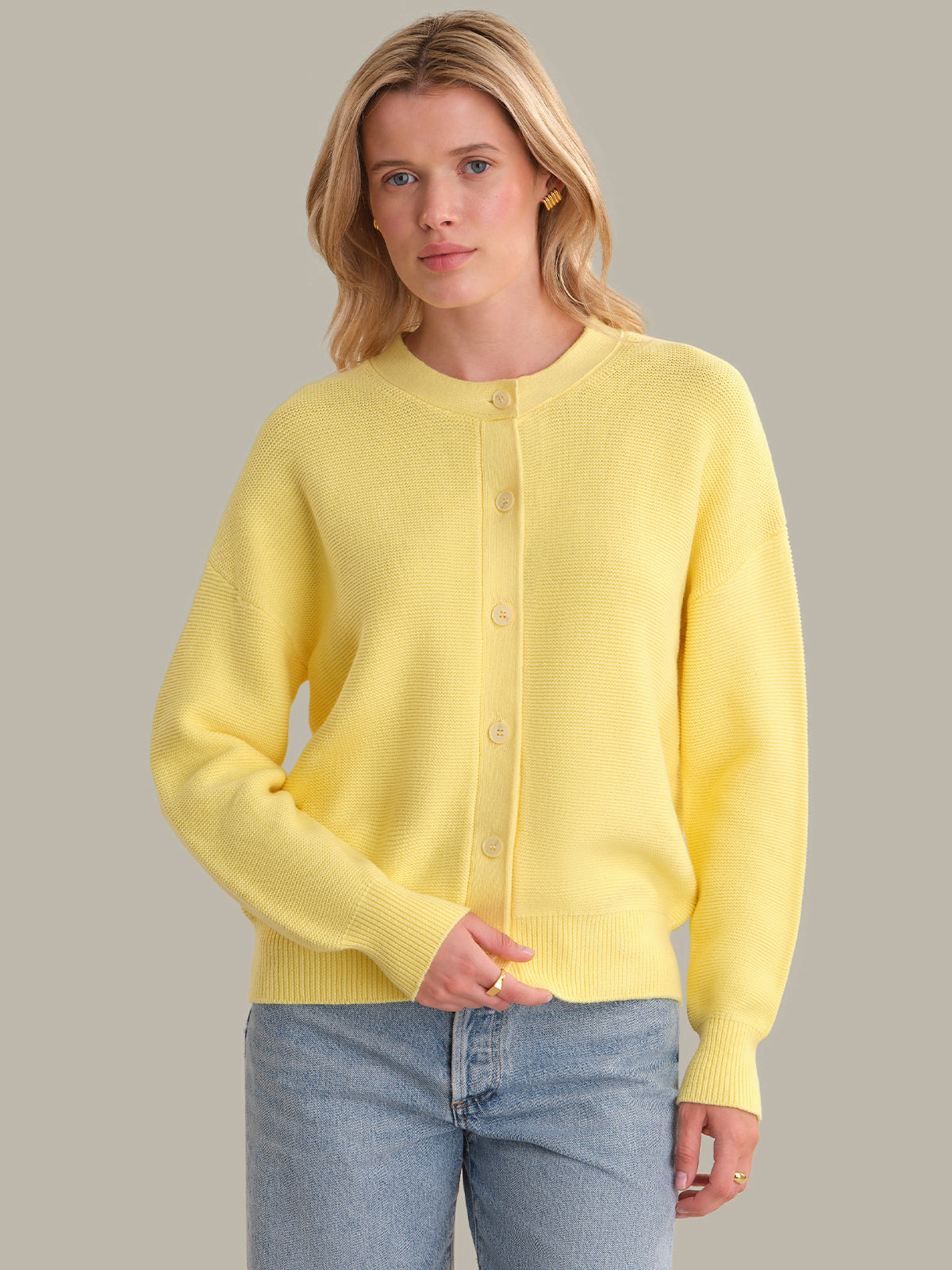 Woman wearing a yellow cardigan against a plain background