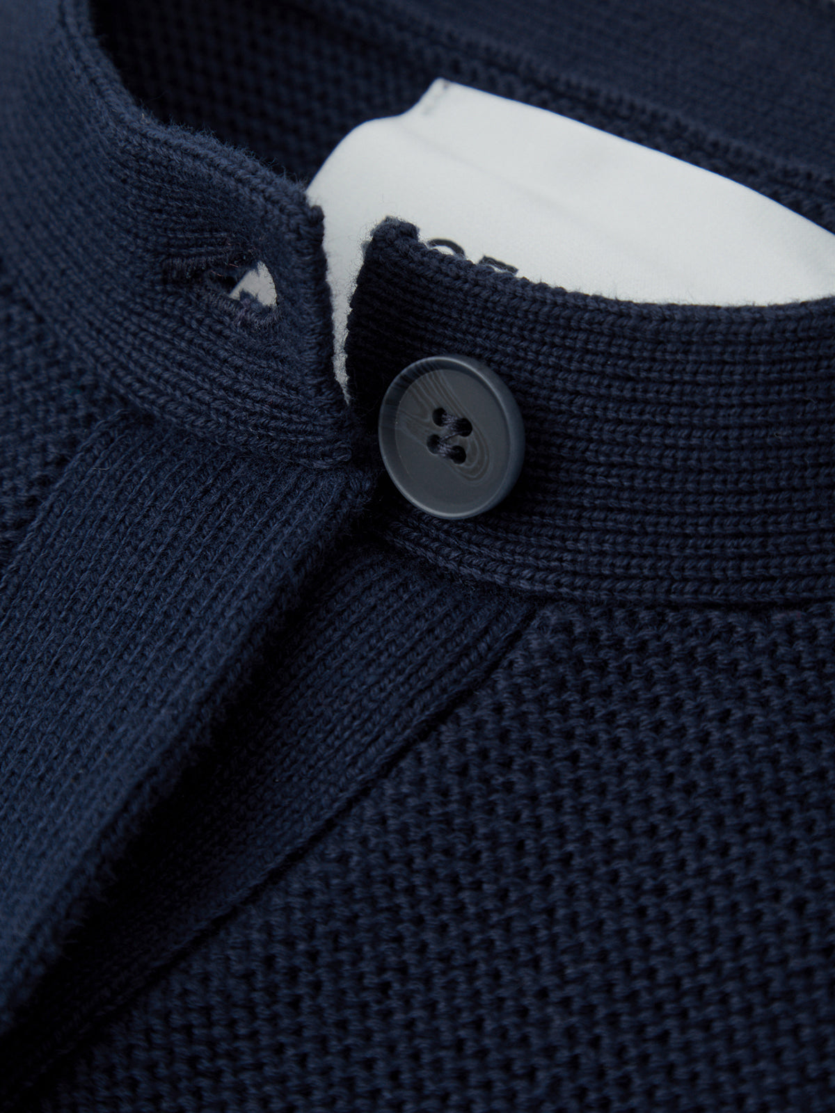 Close-up of a navy blue textured garment with a button