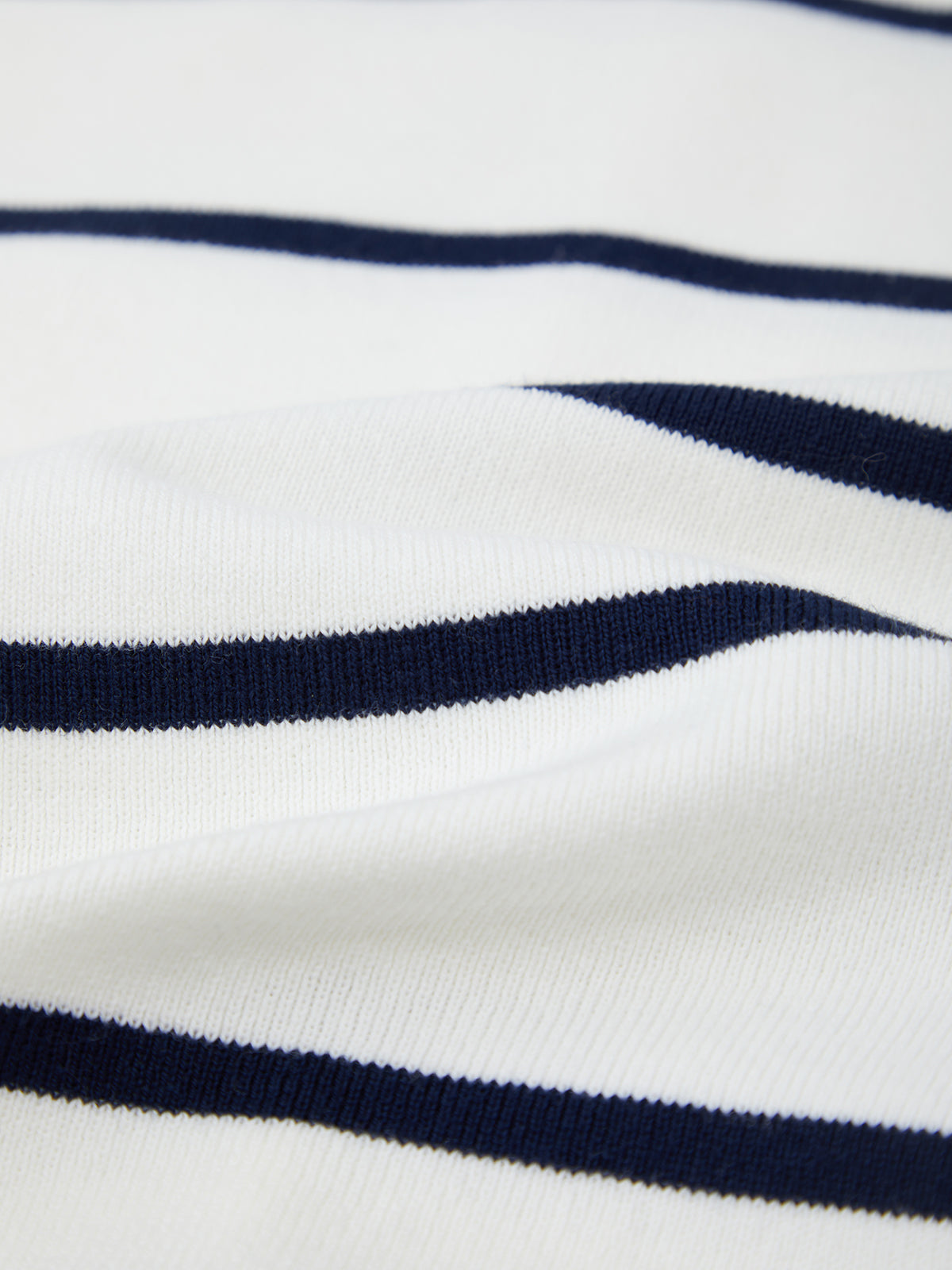 Close-up of 525 America premium cotton fabric featuring evenly spaced horizontal navy blue stripes. Subtle folds and texture showcase the materials softness and fine weave.