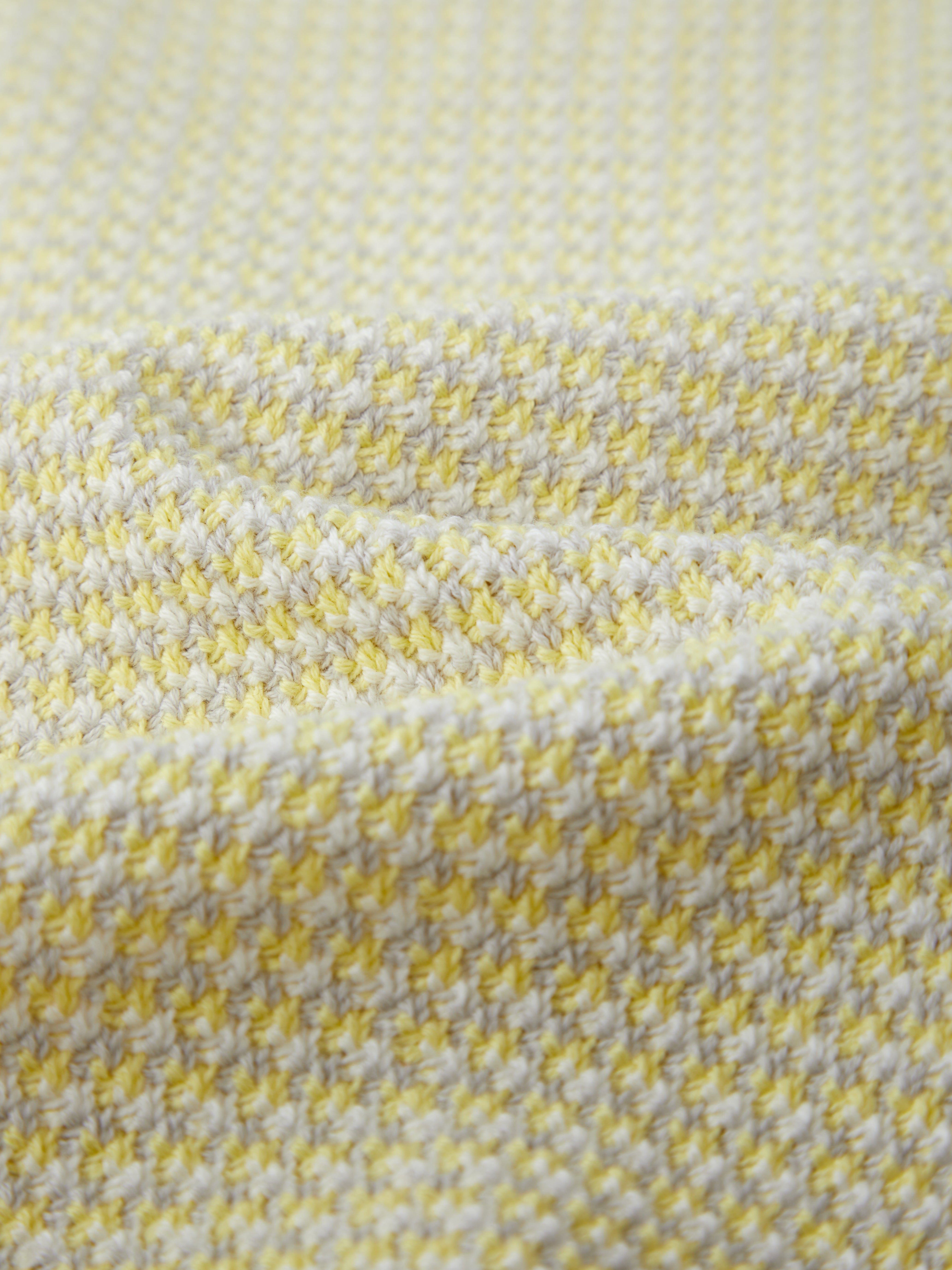 A close-up of 525 America’s textured 100% cotton fabric, showcasing a repeating pattern of yellow and white stitches on a soft, woven surface with gentle folds.