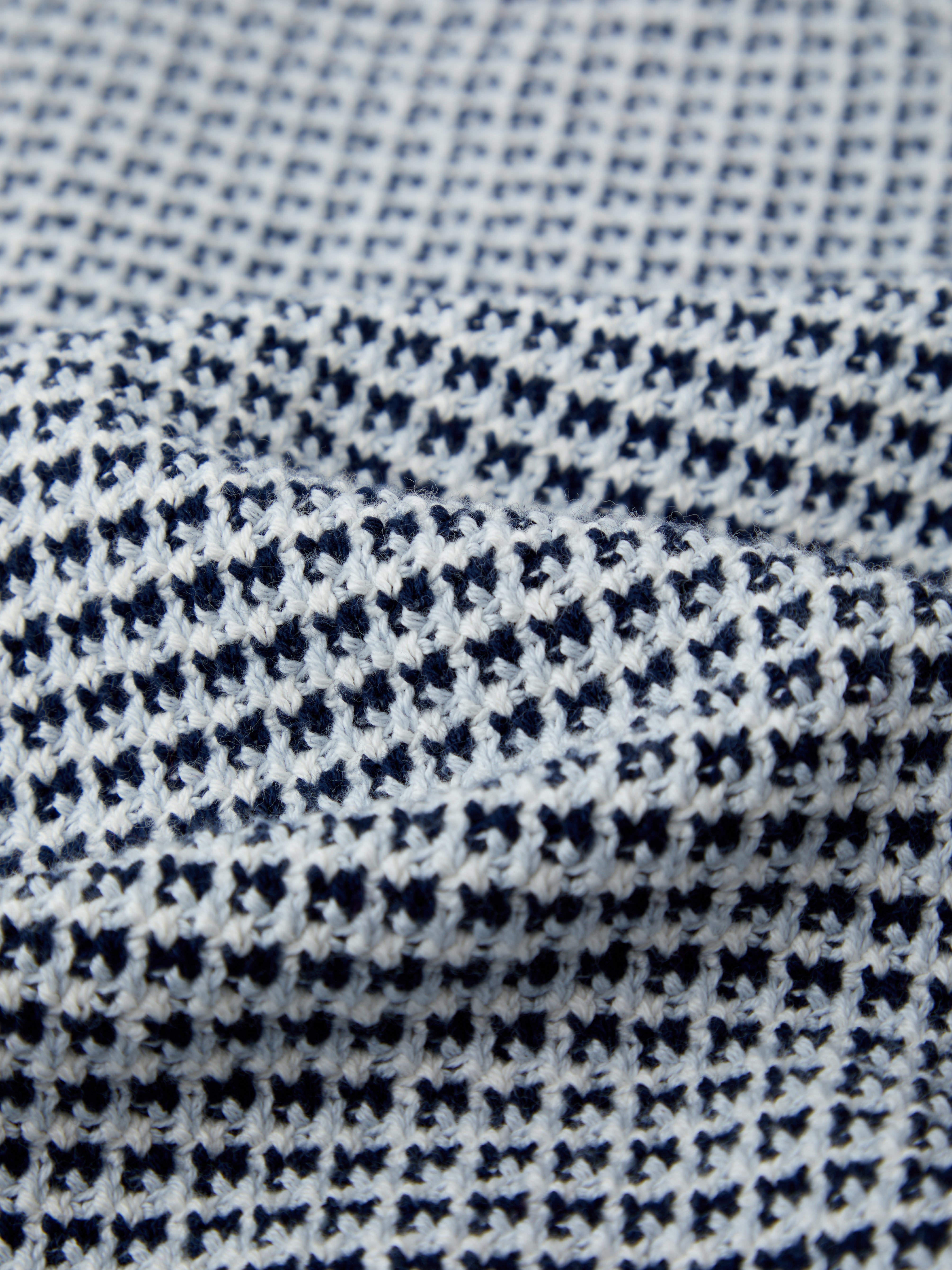 A close-up of 525 America fabric reveals a textured waffle pattern in dark blue and white. Slight wrinkles enhance the depth and structure, making it ideal for puff sleeves or relaxed-fit styles.