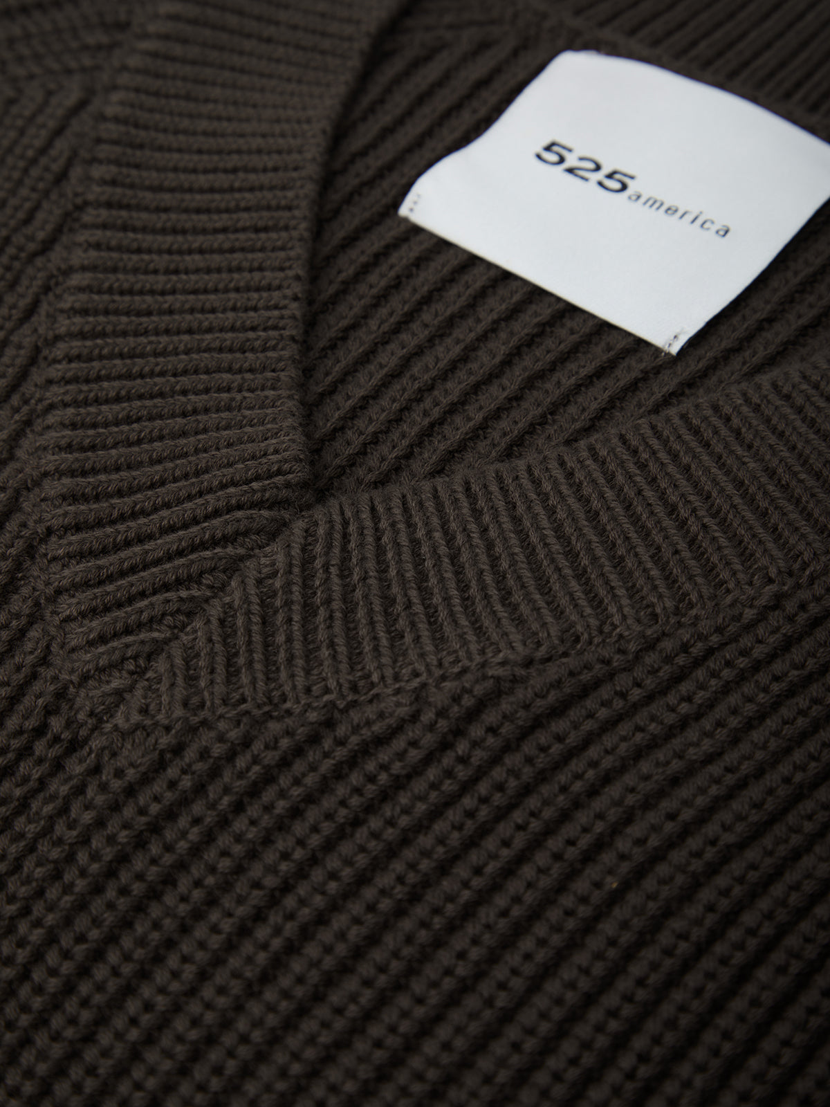 Close-up of a brown ribbed sweater with a visible brand label.