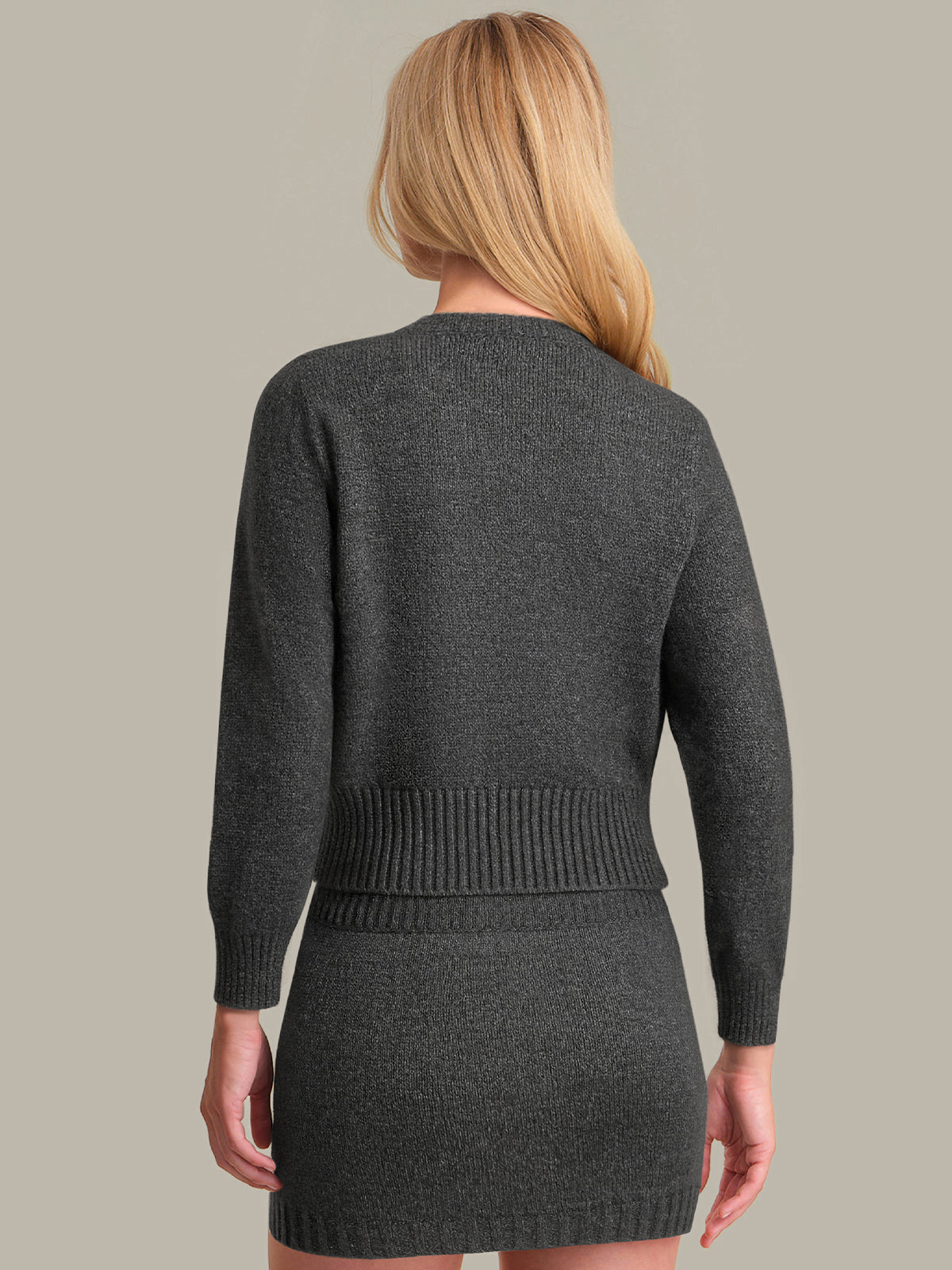 Woman wearing a gray knit skirt set on a neutral background