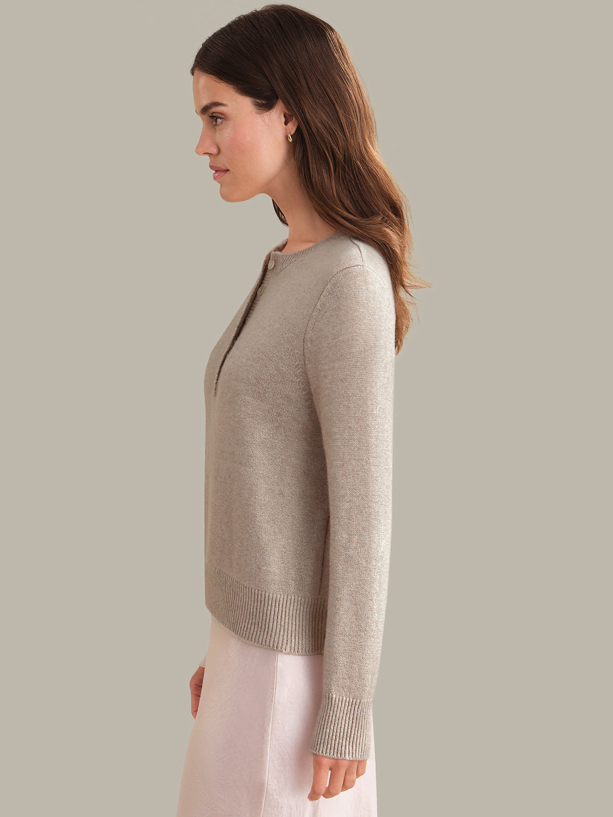 Woman wearing a beige sweater against a plain background