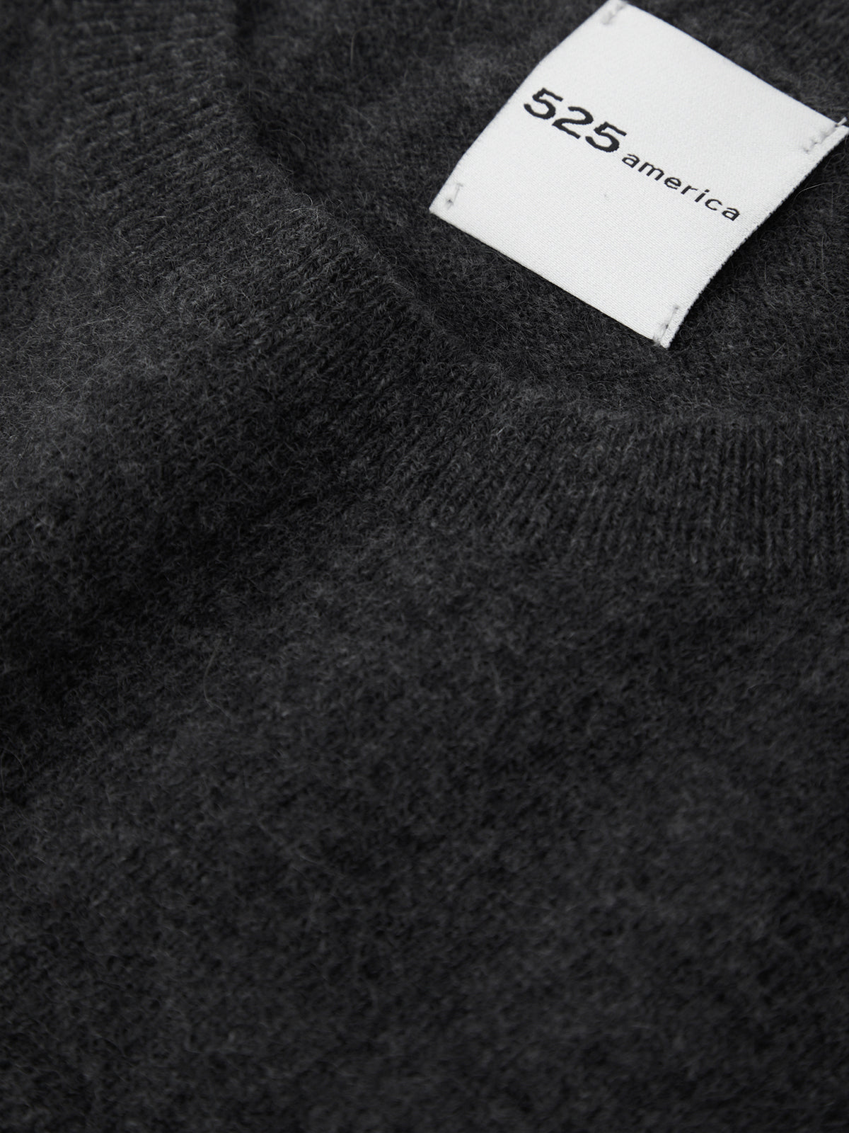 Black sweater with a visible brand label on a dark background