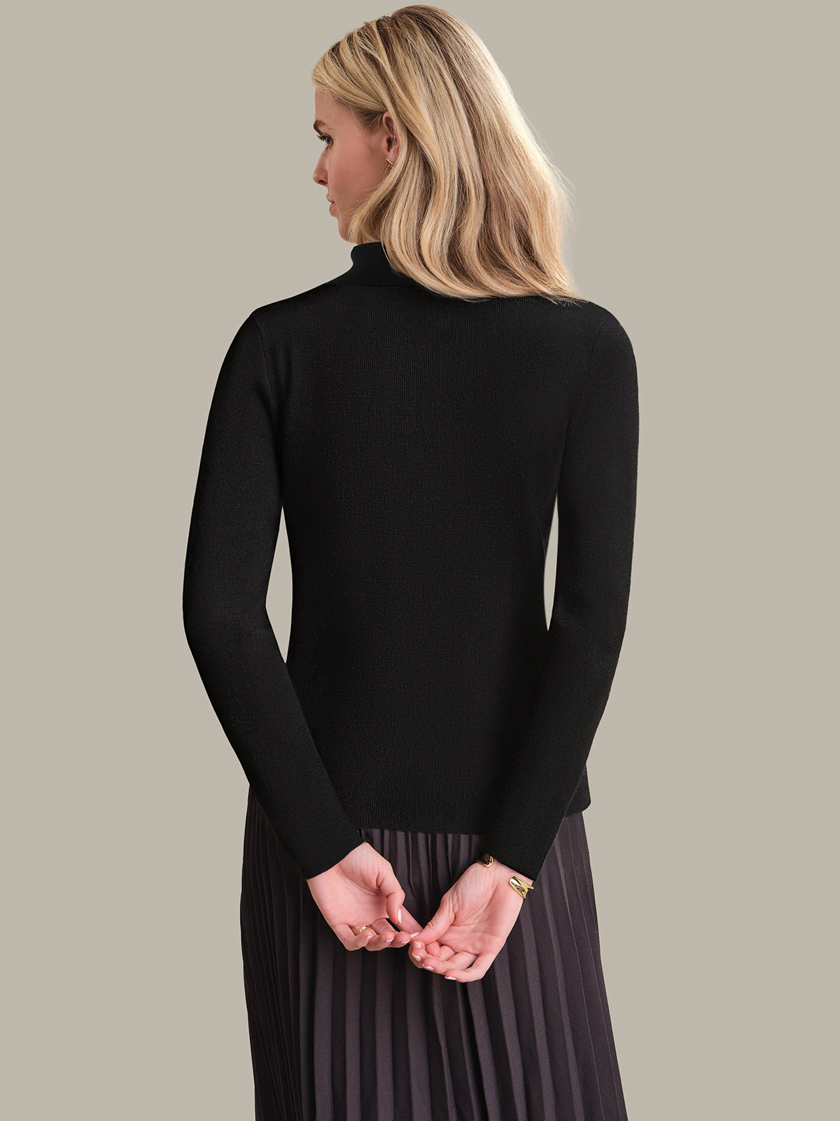 Woman wearing a black turtleneck sweater against a plain background