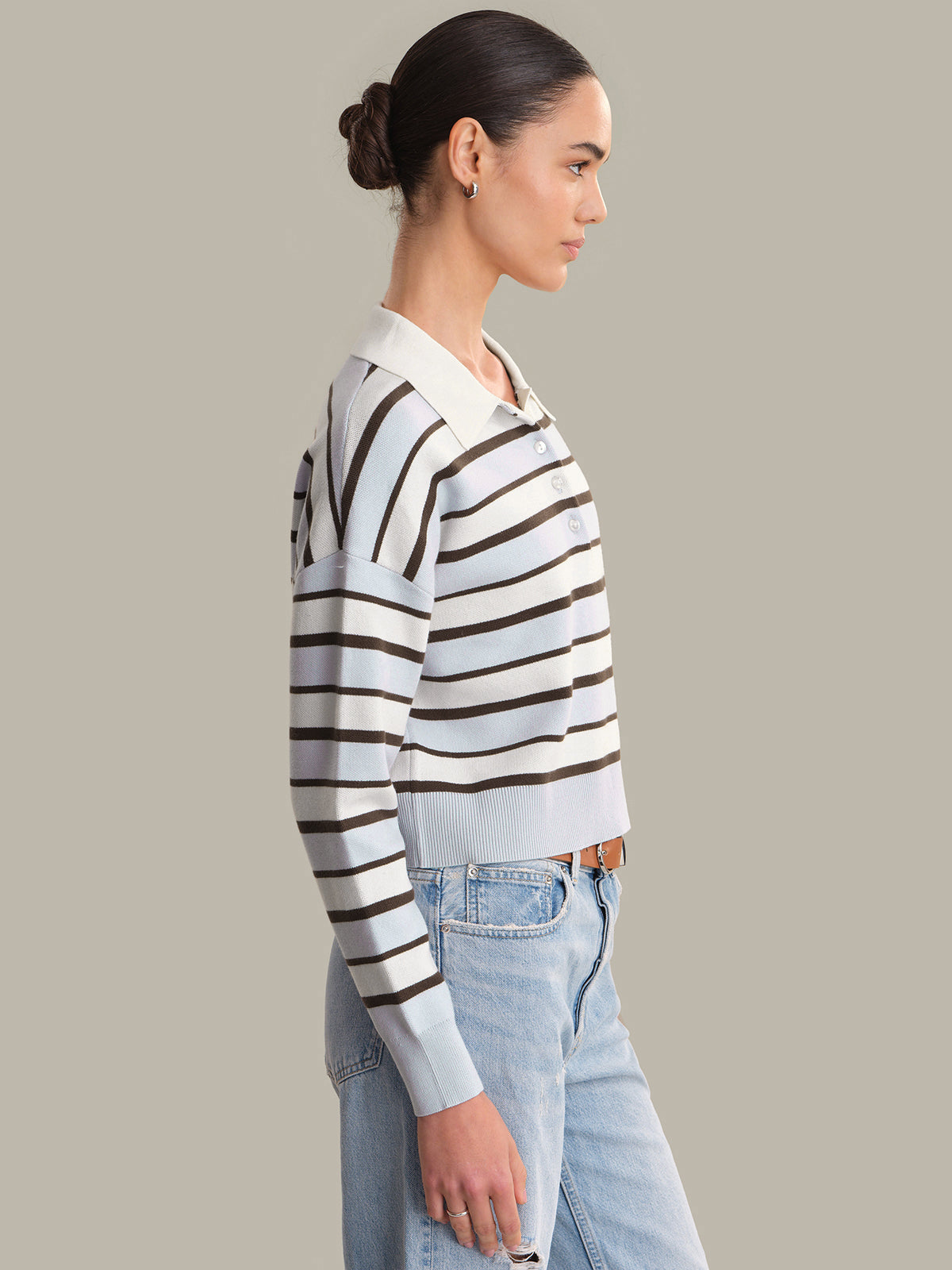 Woman wearing a striped sweater and jeans against a plain background