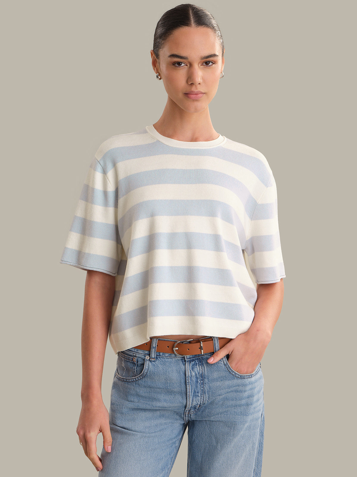 Woman wearing a striped sweater and jeans against a plain background