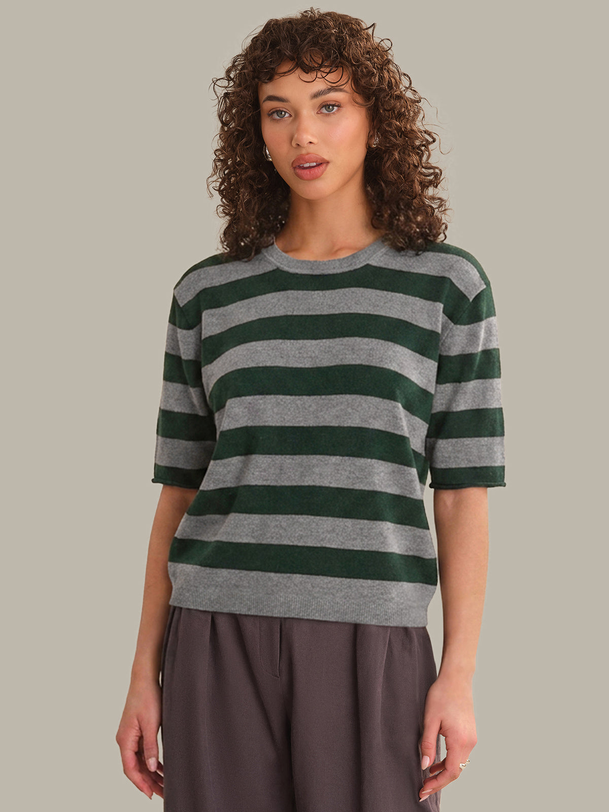 Woman wearing a green and gray striped sweater against a plain background