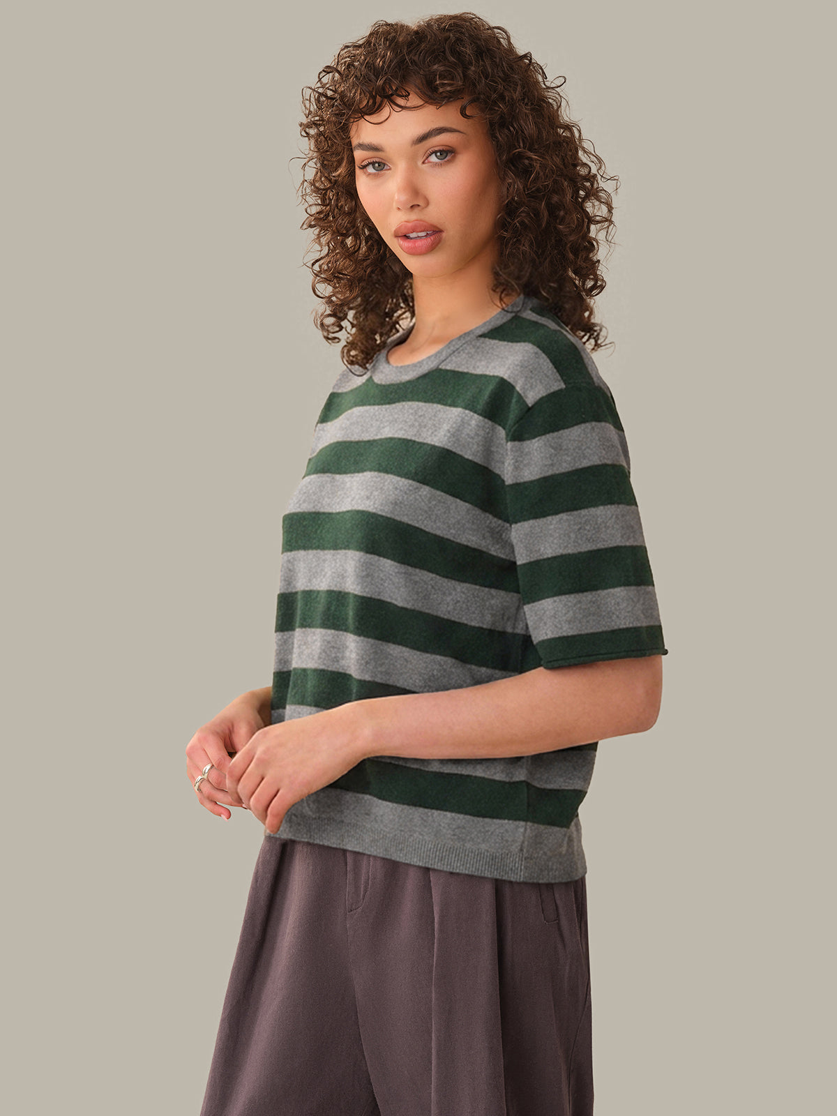 Woman wearing a green and gray striped shirt against a plain background