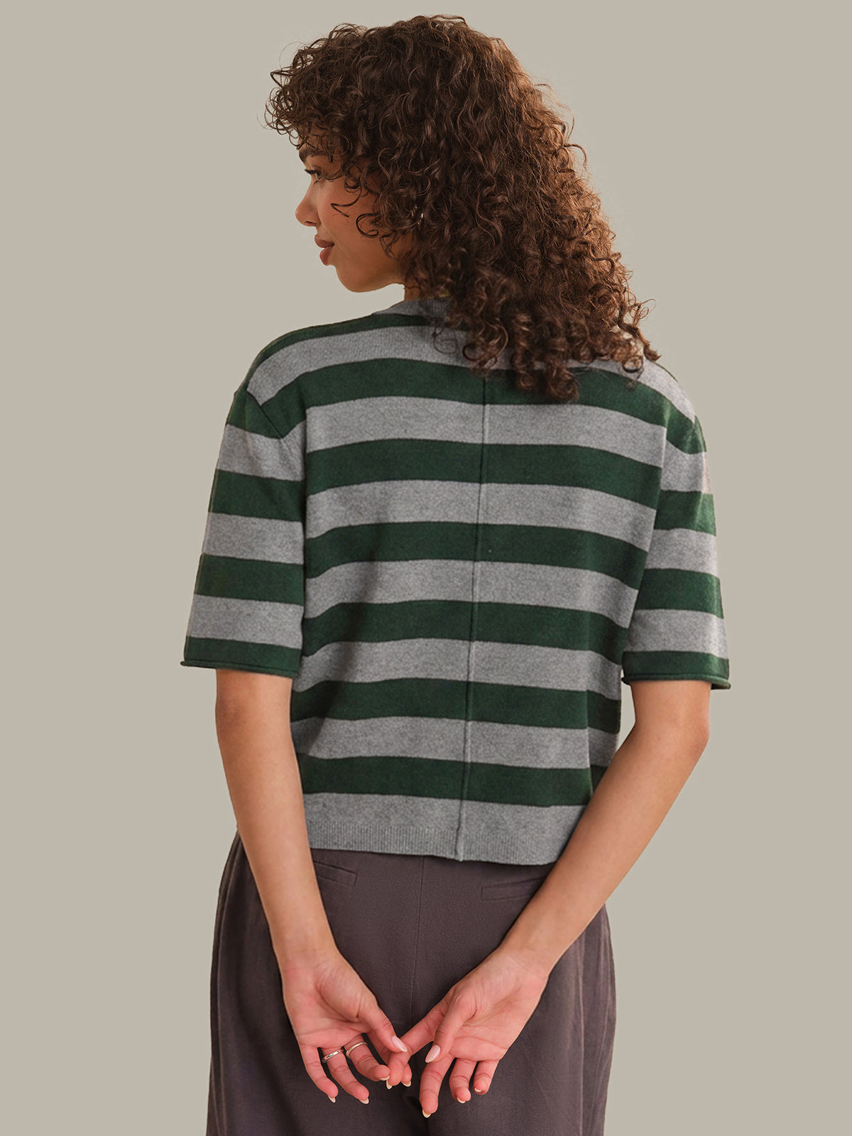 Person wearing a green and gray striped shirt against a plain background