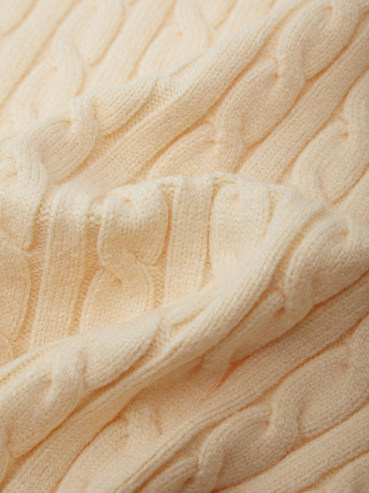 Close-up of a beige cable knit sweater fabric