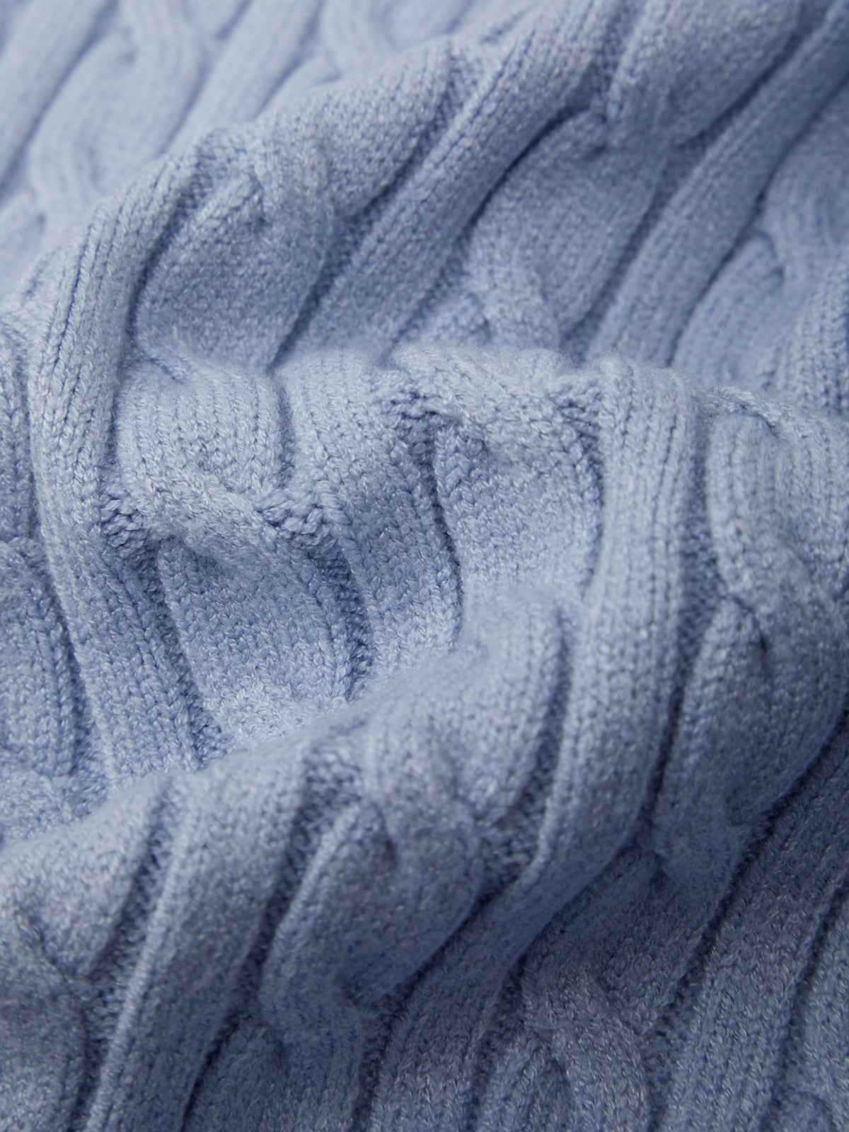 Close-up of a textured blue fabric with cable knit pattern