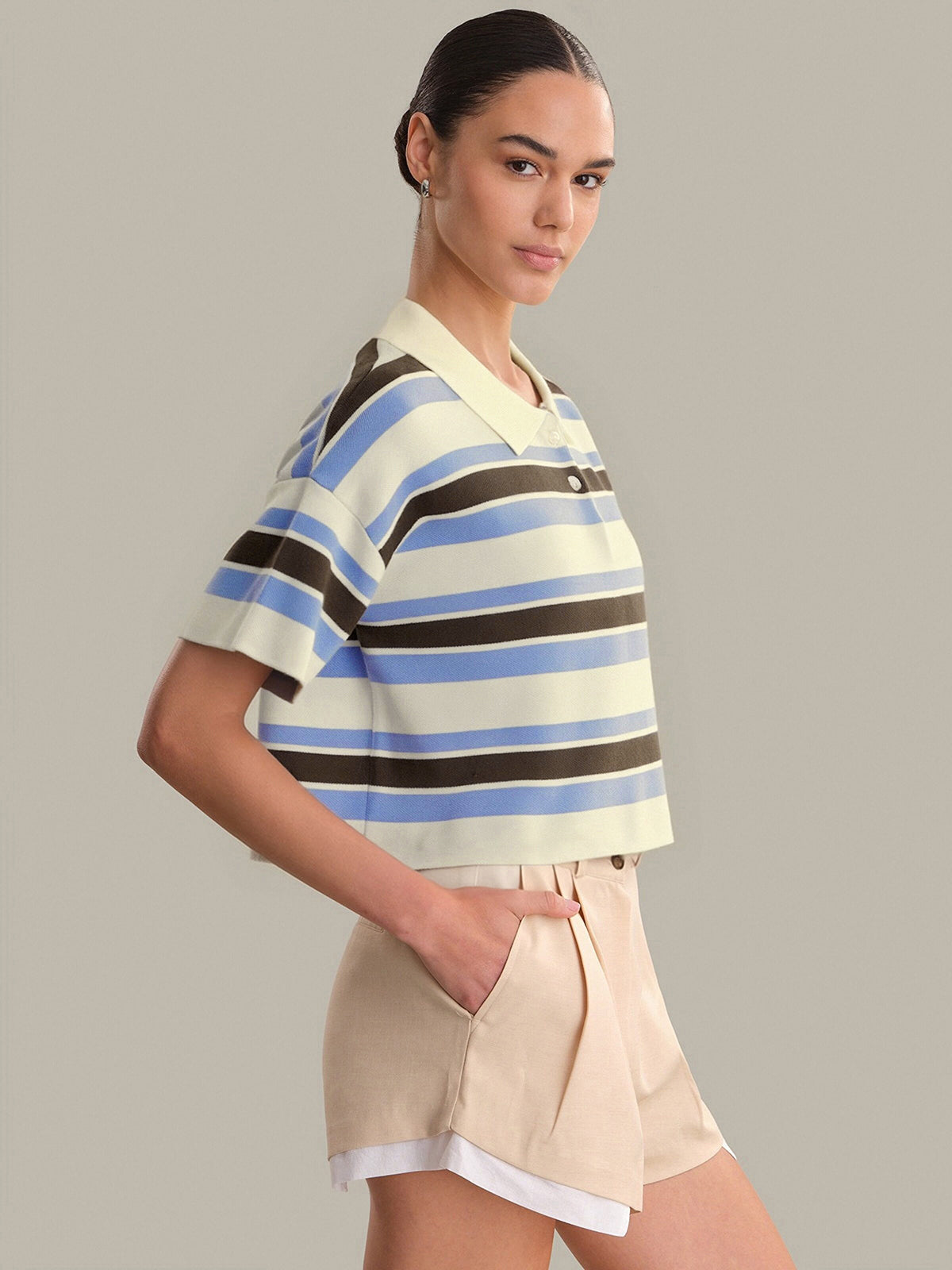 Woman wearing a striped shirt and shorts on a plain background
