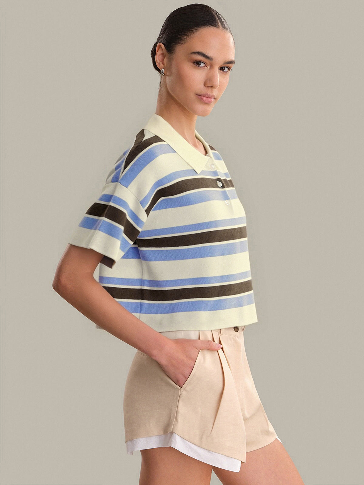 Woman wearing a striped shirt and shorts on a plain background