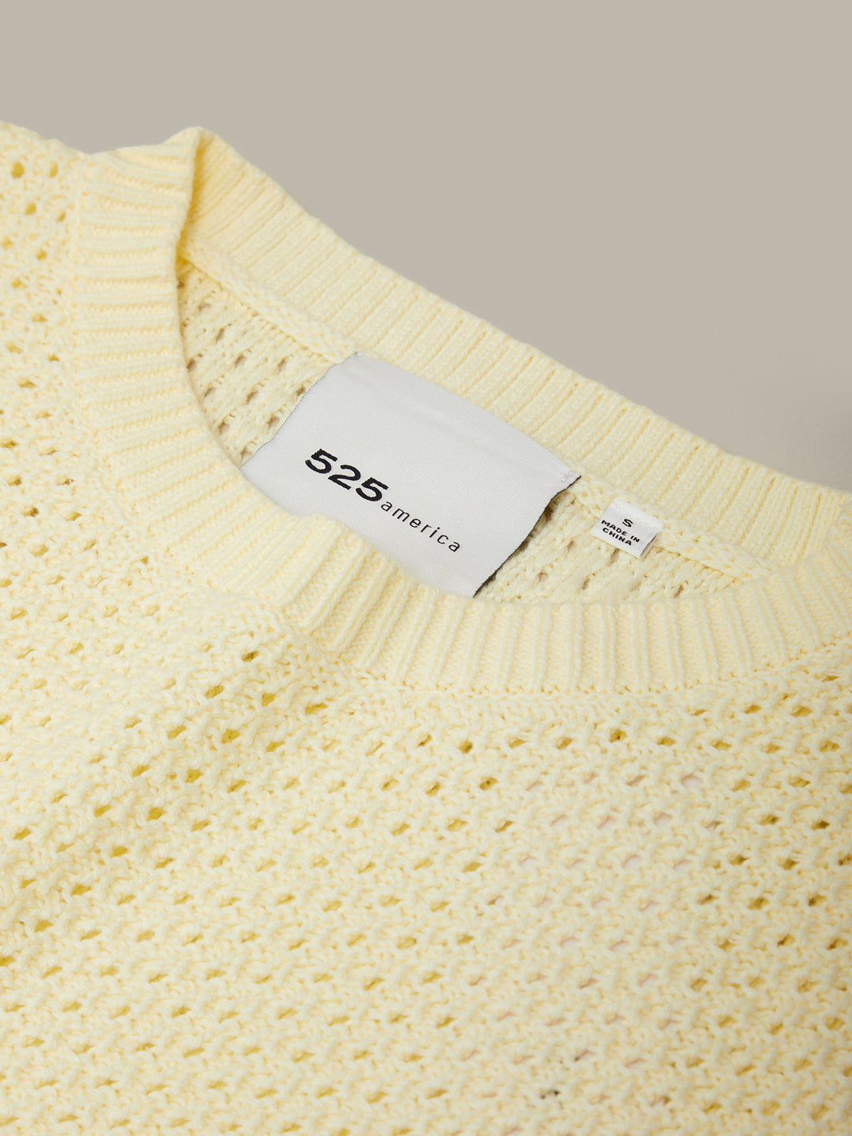 Yellow sweater with a label on a beige background