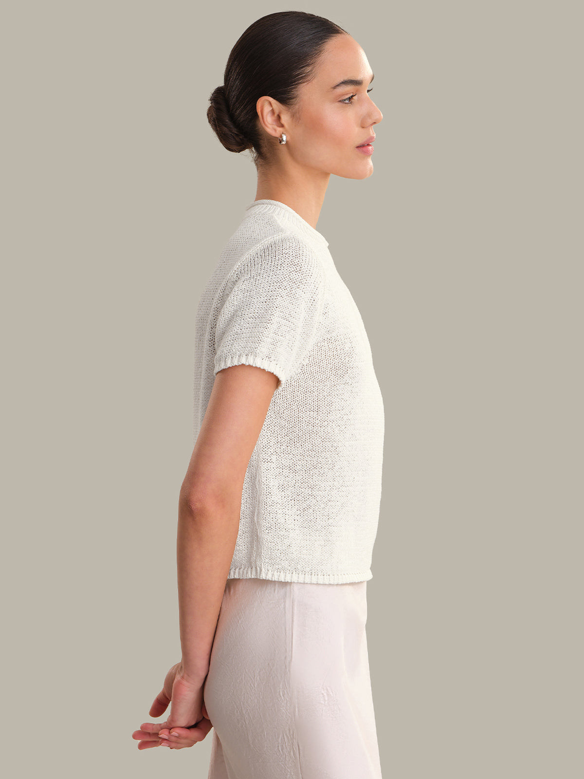 Woman wearing a white top and skirts against a neutral background