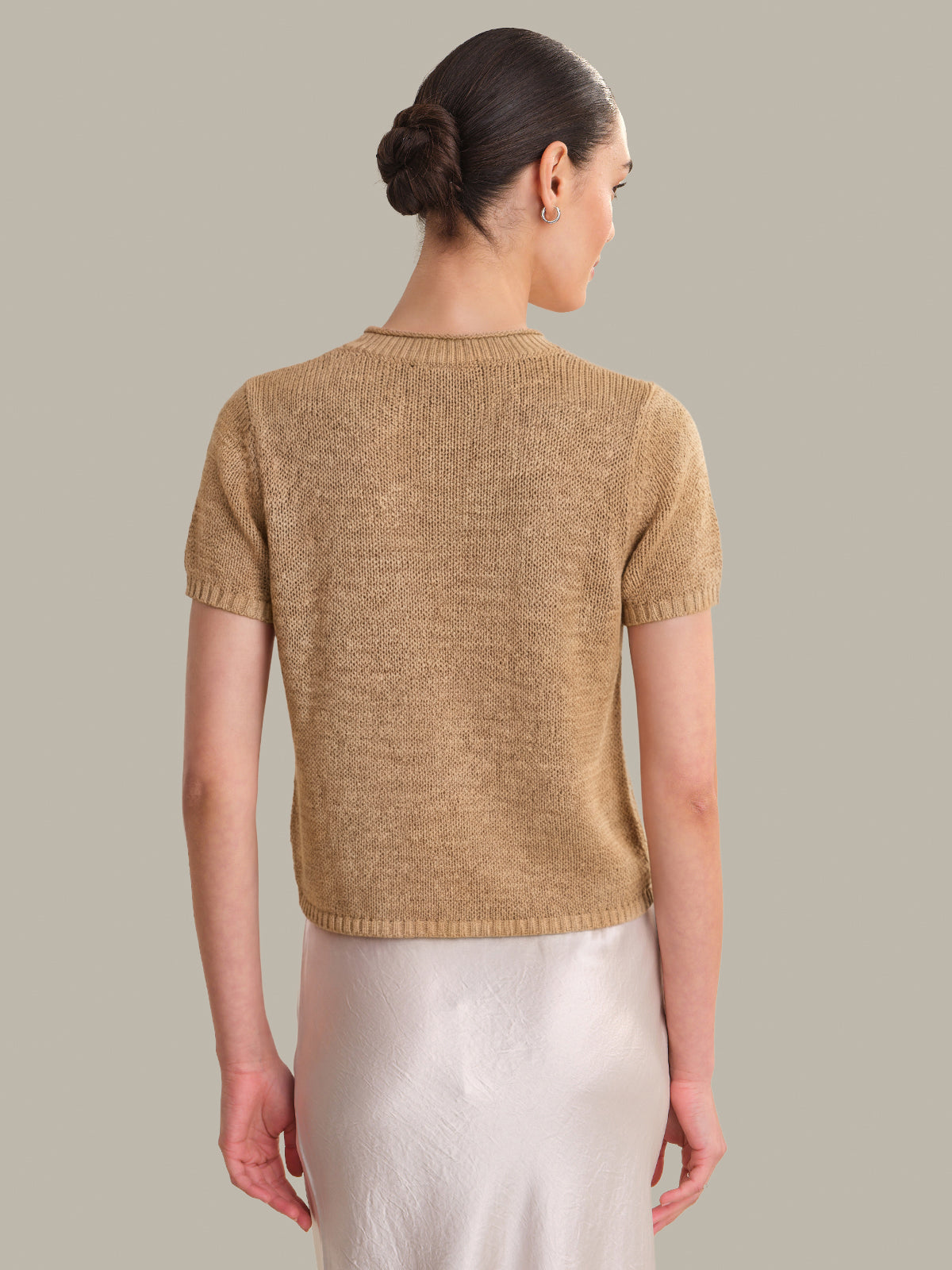 Woman wearing a beige knitted sweater against a plain background