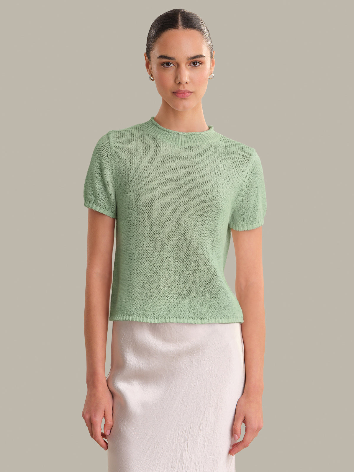Woman wearing a green knitted top against a plain background