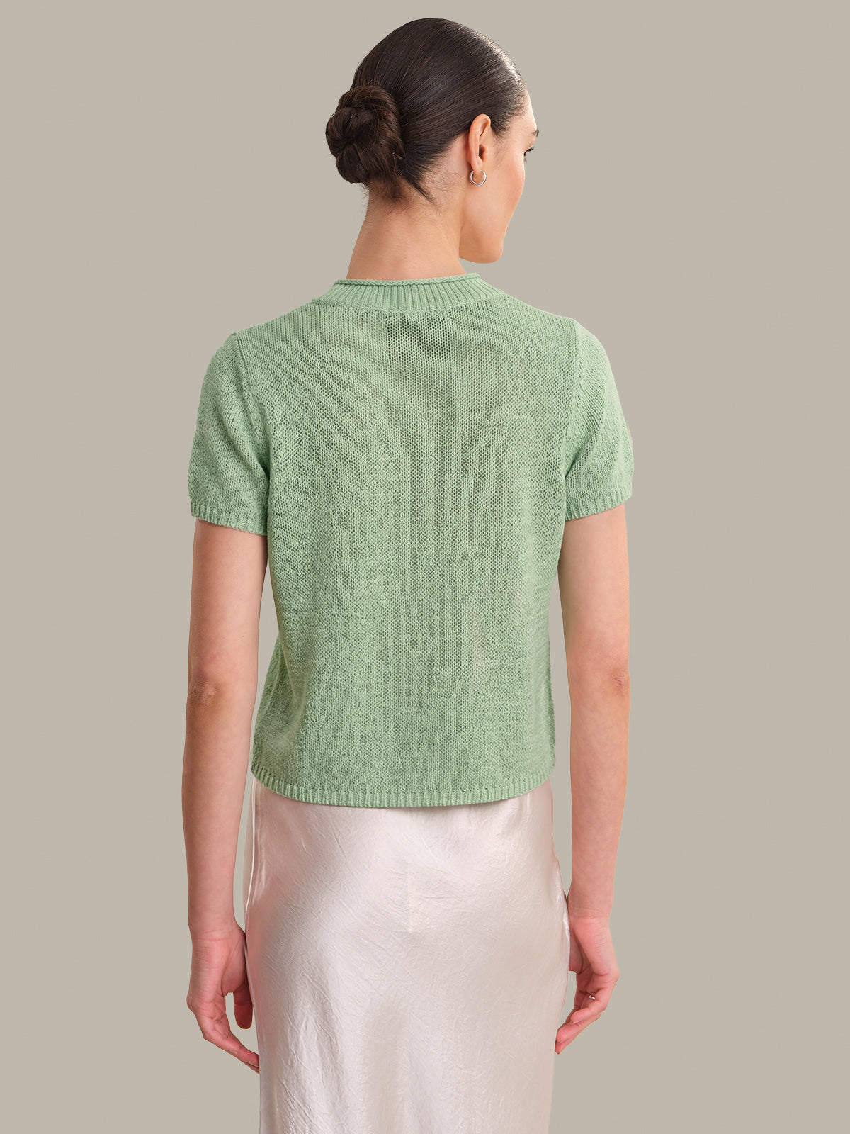 Woman wearing a green knitted top against a plain background