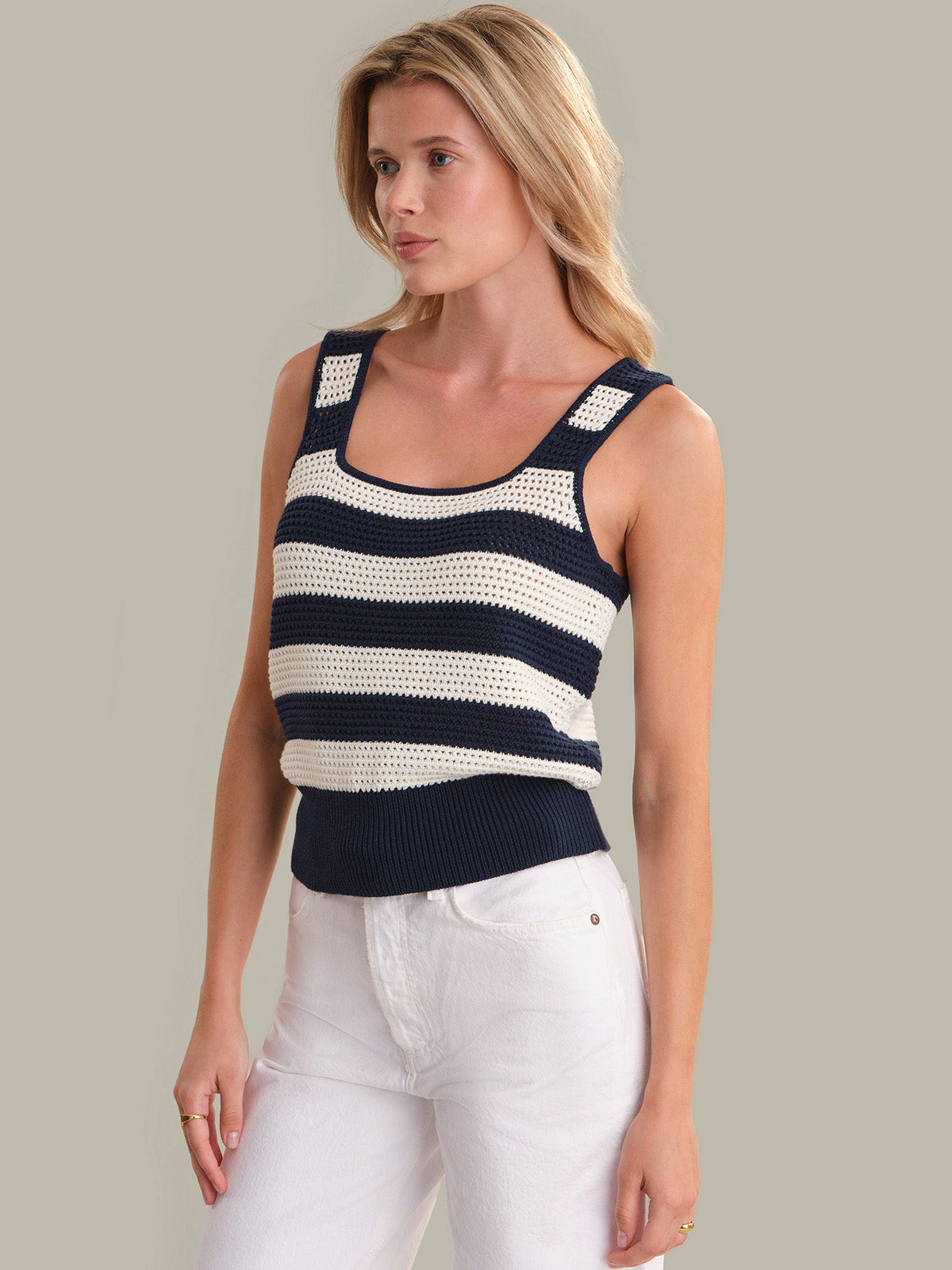 Woman wearing a navy and white striped tank top against a neutral background