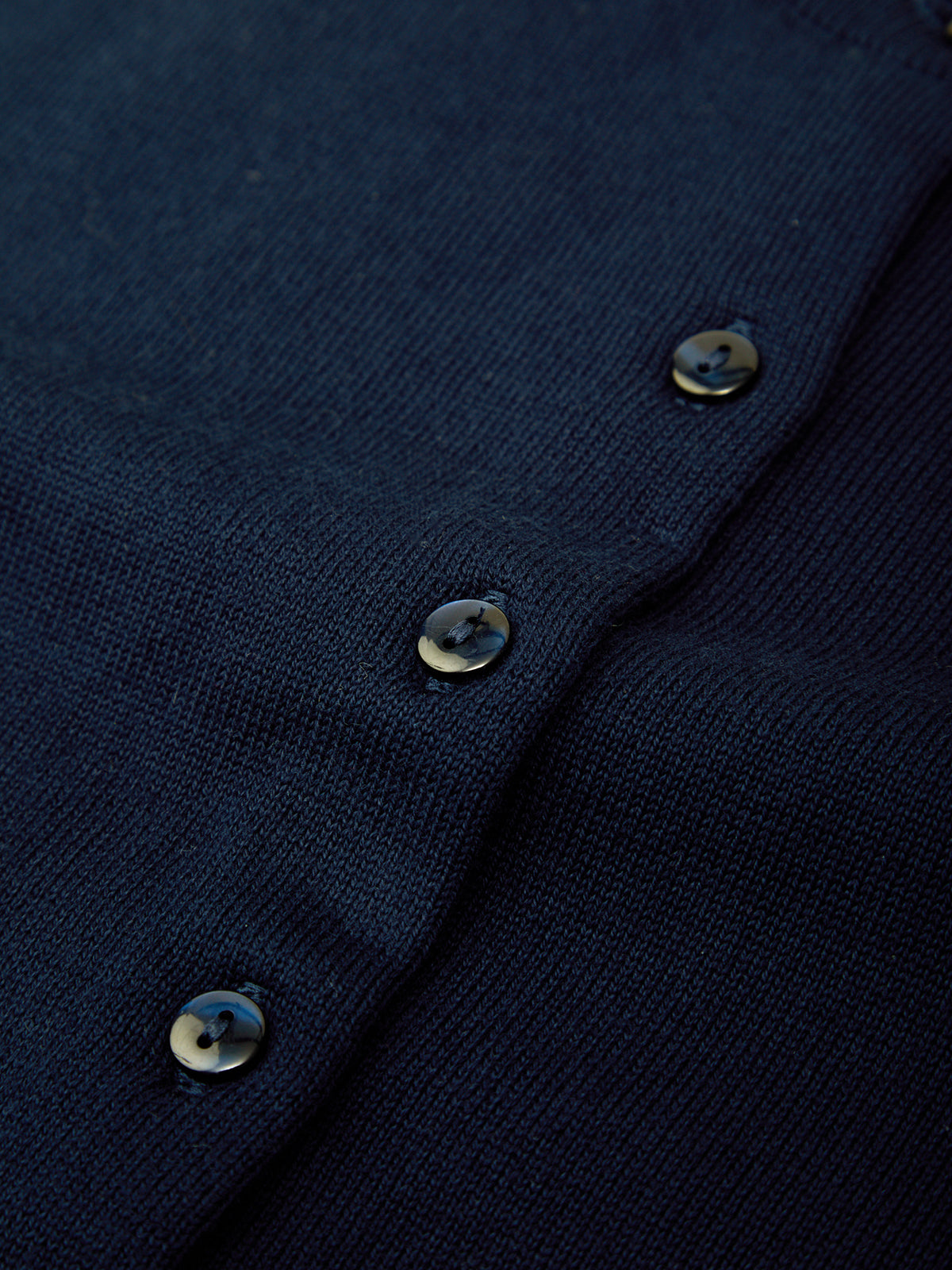 Close-up of a navy blue garment with buttons on a dark background
