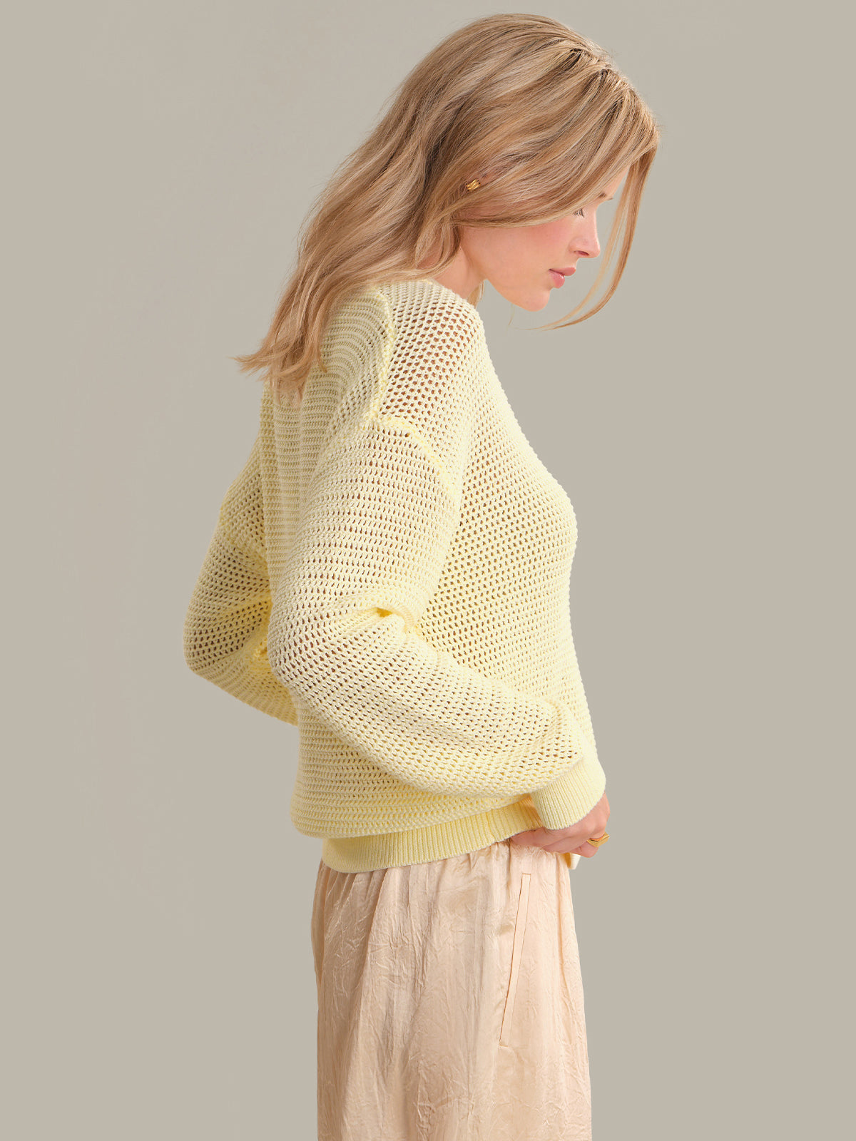 Woman wearing a light yellow knitted sweater against a plain background