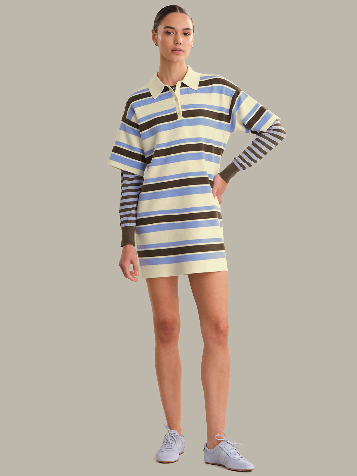 Woman wearing a striped dress with long sleeves on a plain background