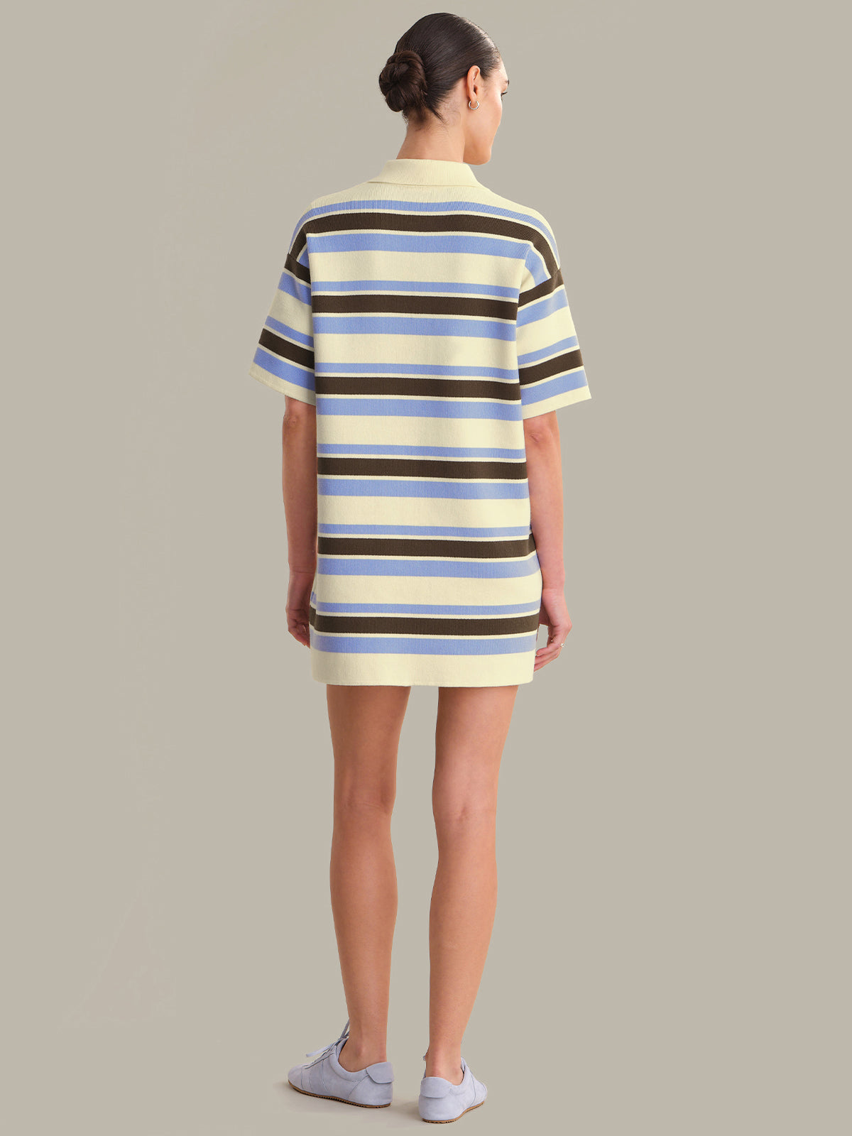 Person wearing a striped dress with a neutral background