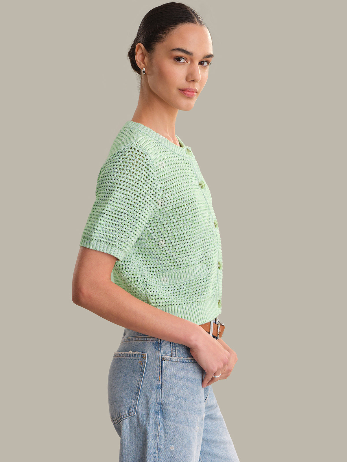 Woman wearing a light green crochet top against a gray background