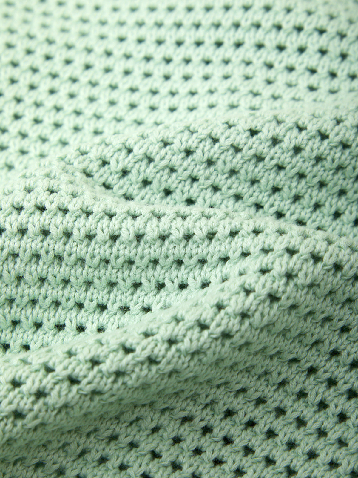 Close-up of a textured green fabric with a diamond pattern