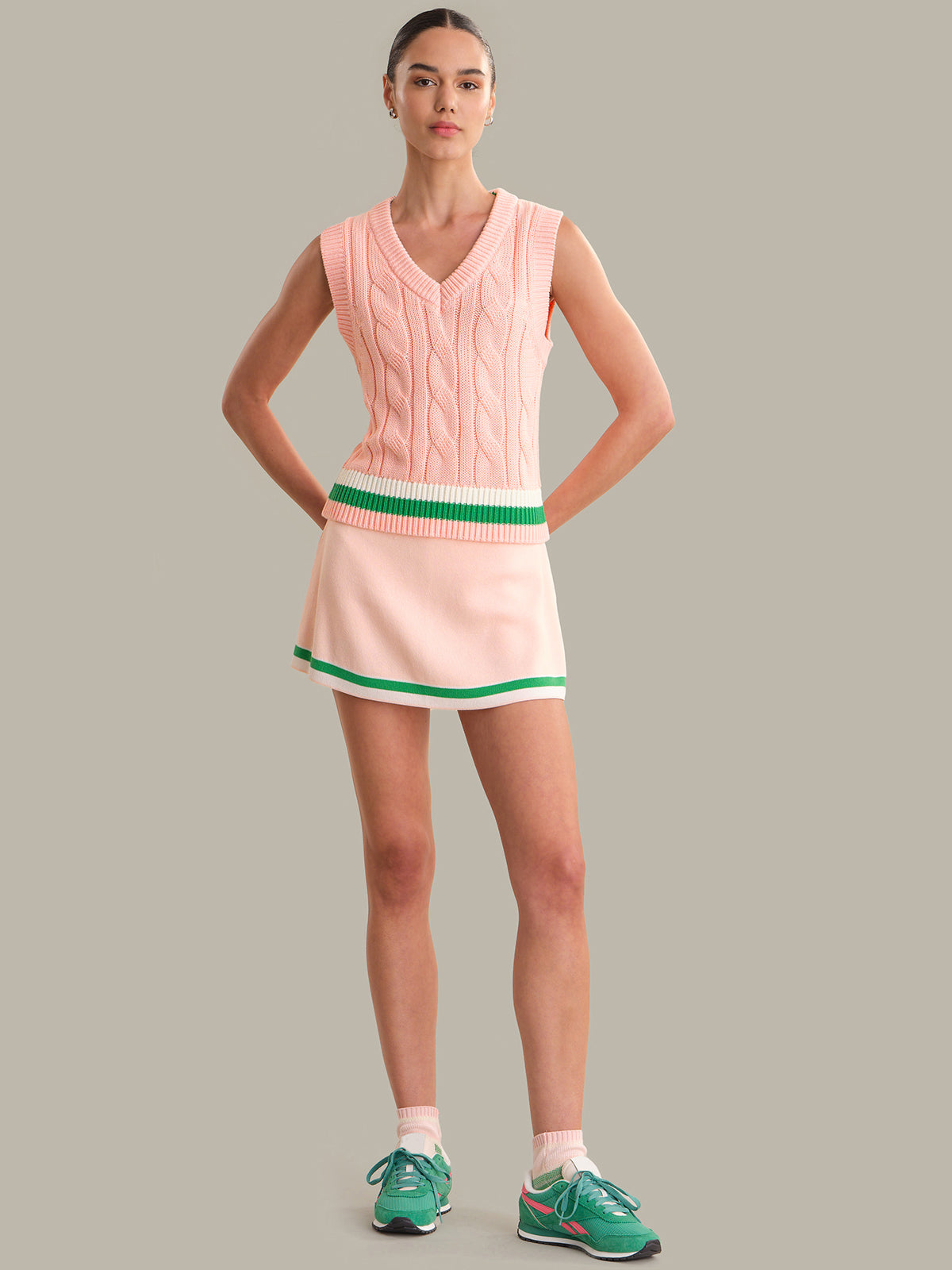 Woman wearing a pink dress with green trim on a gray background