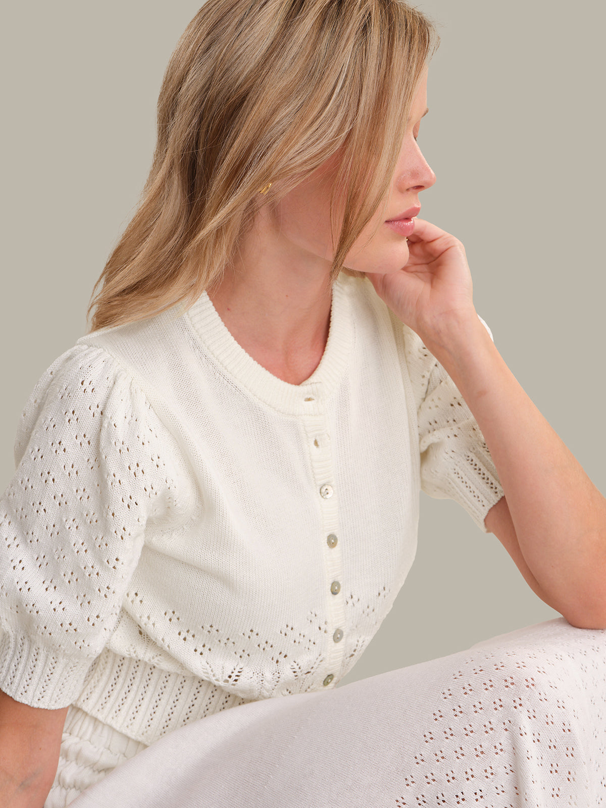 Woman wearing a white blouse with a subtle pattern on a neutral background