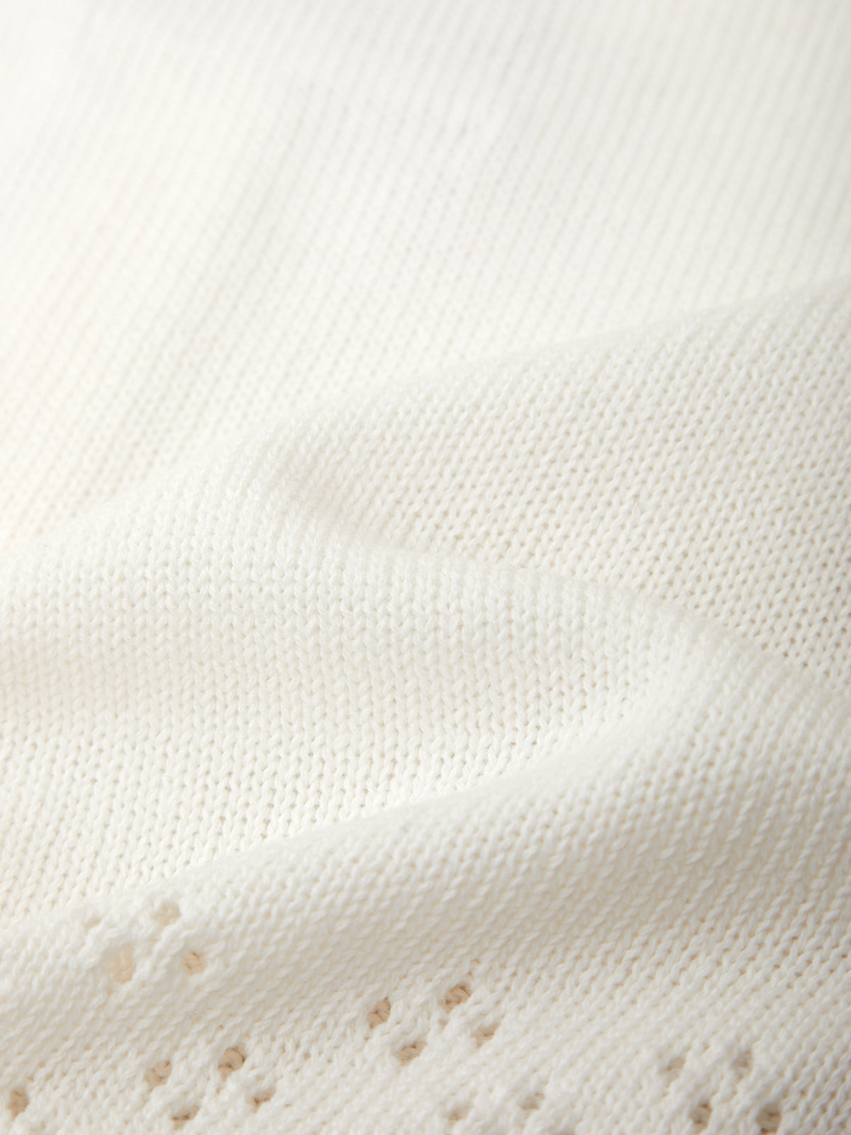 Close-up of a textured white fabric surface with small brown spots.
